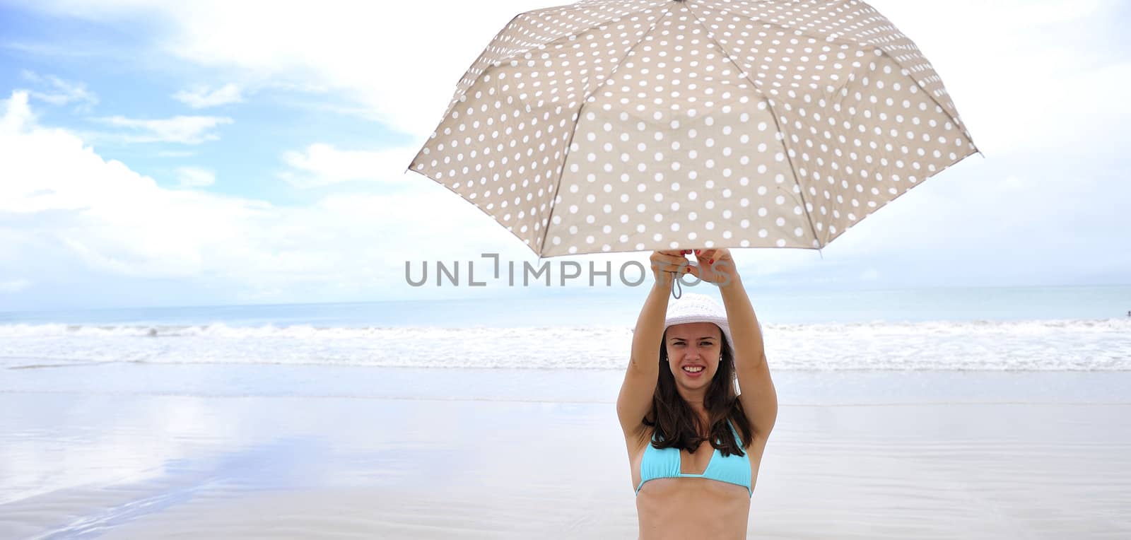 woman jumping on a tropical beach holding an umbrella 
