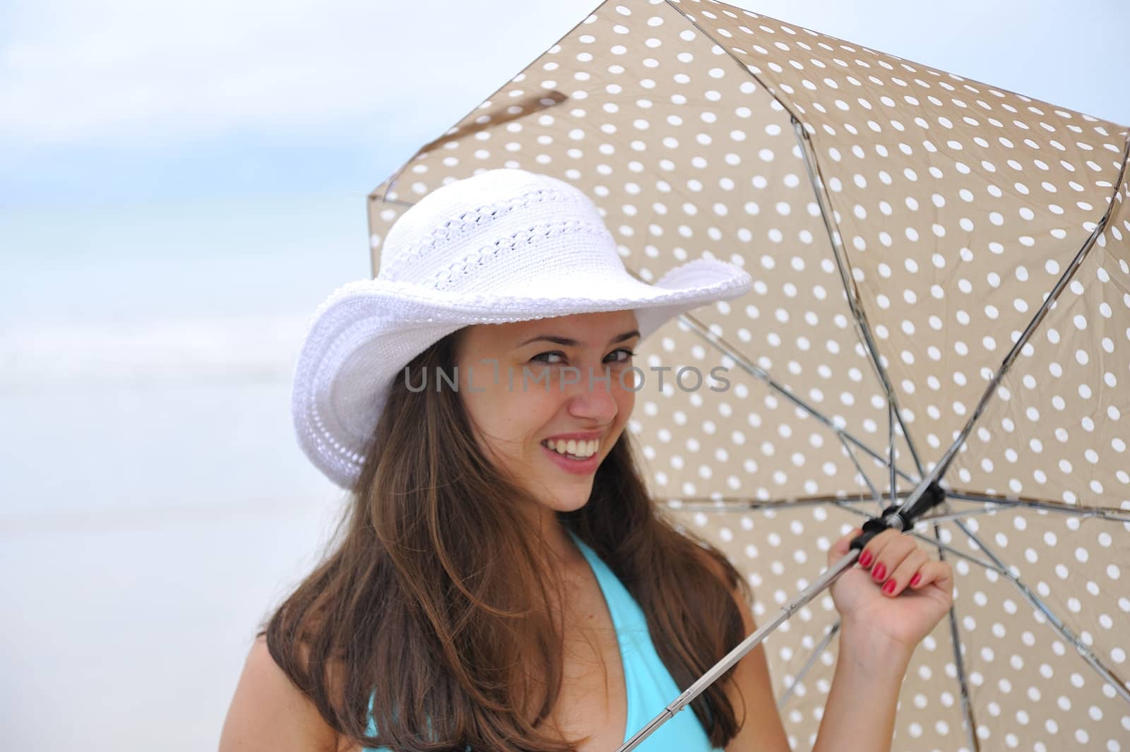 woman jumping on a tropical beach holding an umbrella 
