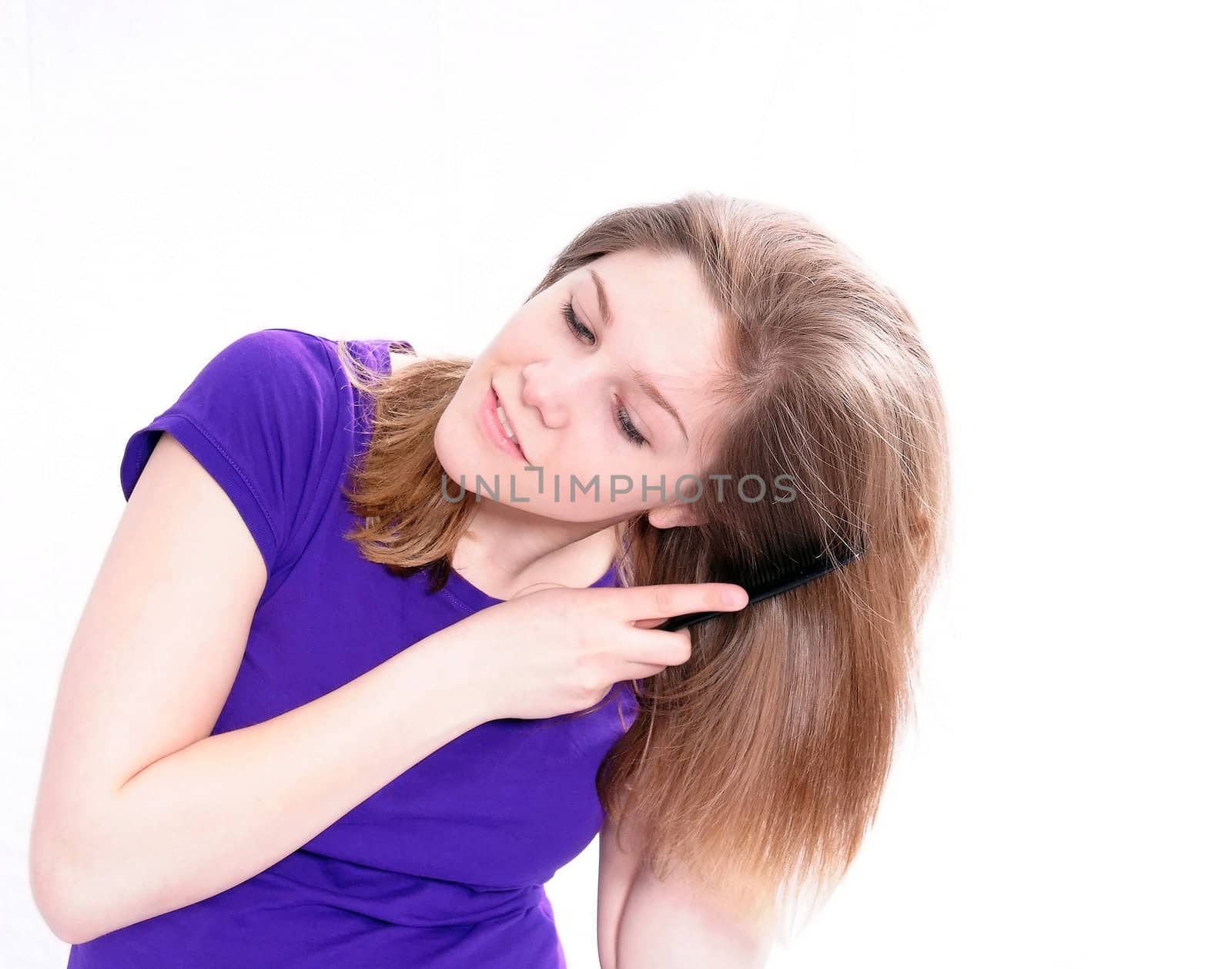 Studio Shot of a beautiful girl in a blue t-shirt dressing her hair, isolated on white background