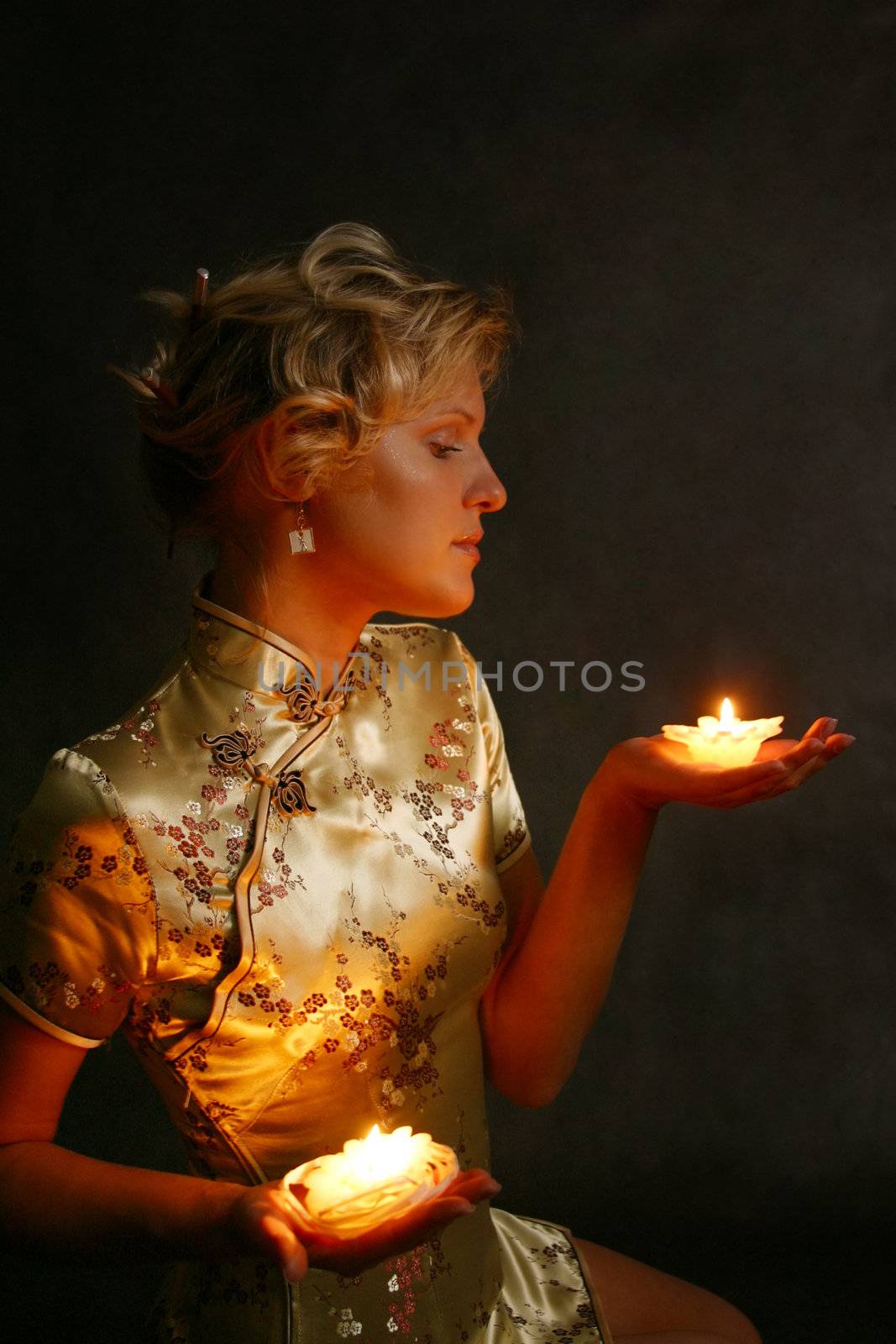 The beautiful blonde with candles on a dark background