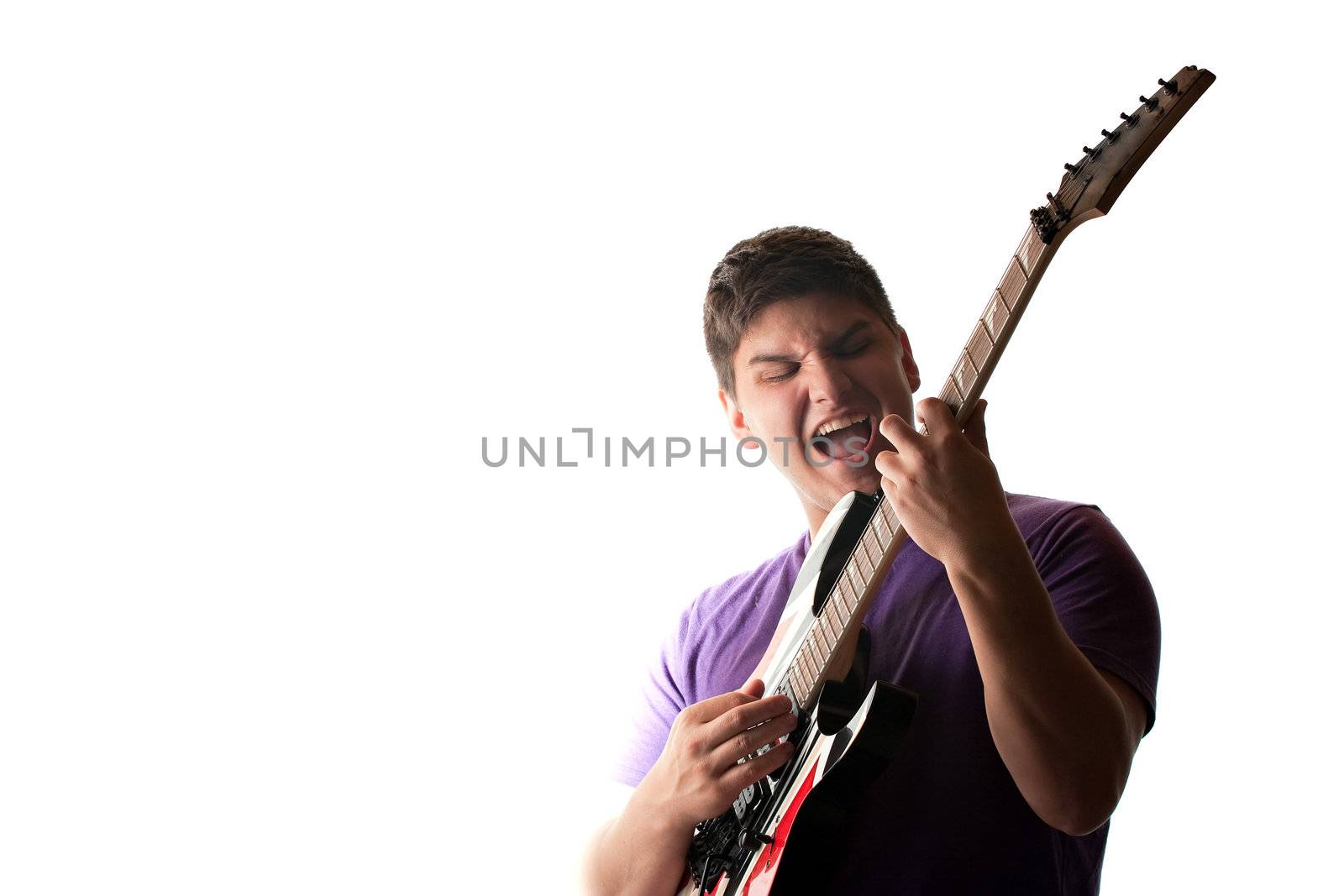 A man in his late teens rocks out while playing his electric guitar.