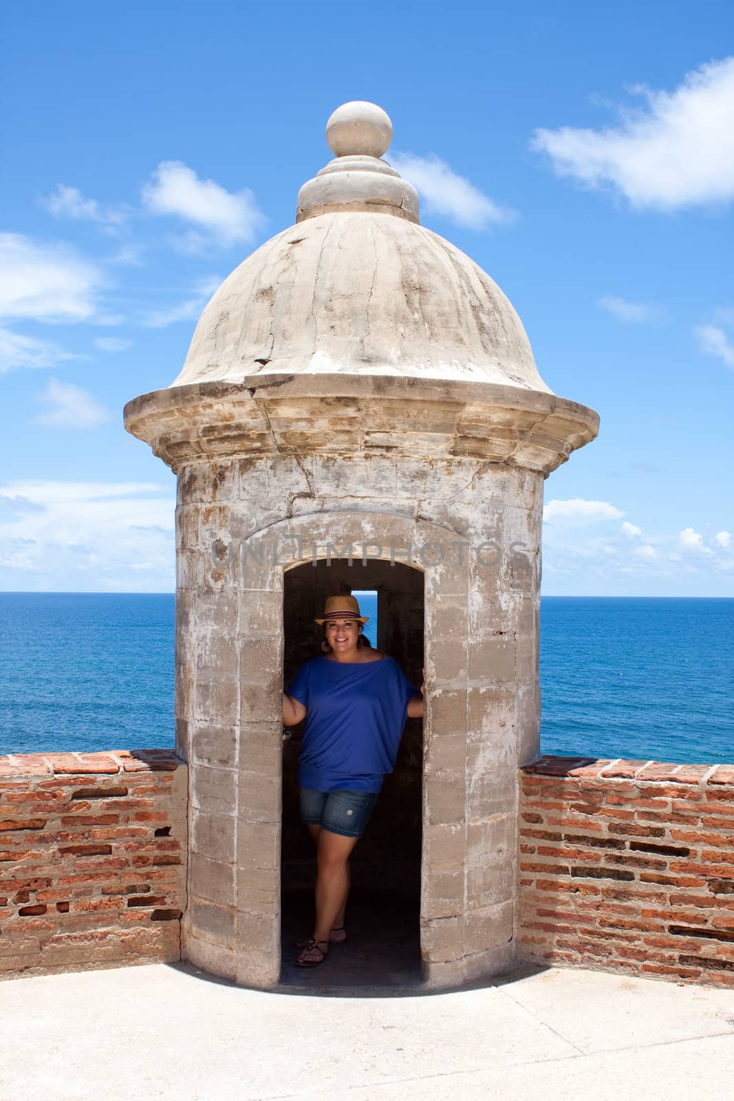 A tourist poses in an old fort watch tower located in Old San Juan Puerto Rico at the historic San Cristobal fortification.