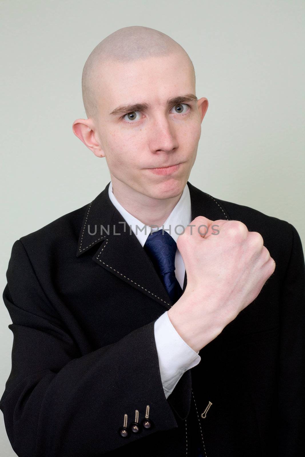 The young man in a suit threatens with a fist