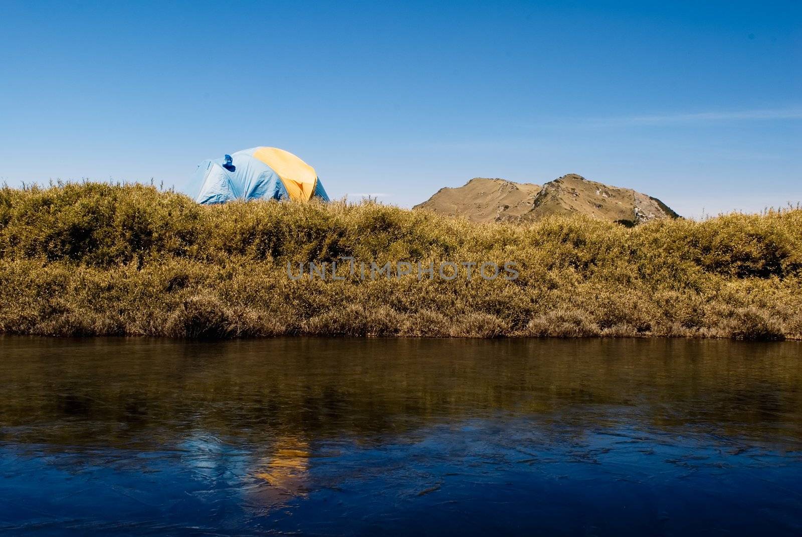 Tent and iced lake in high mountain.