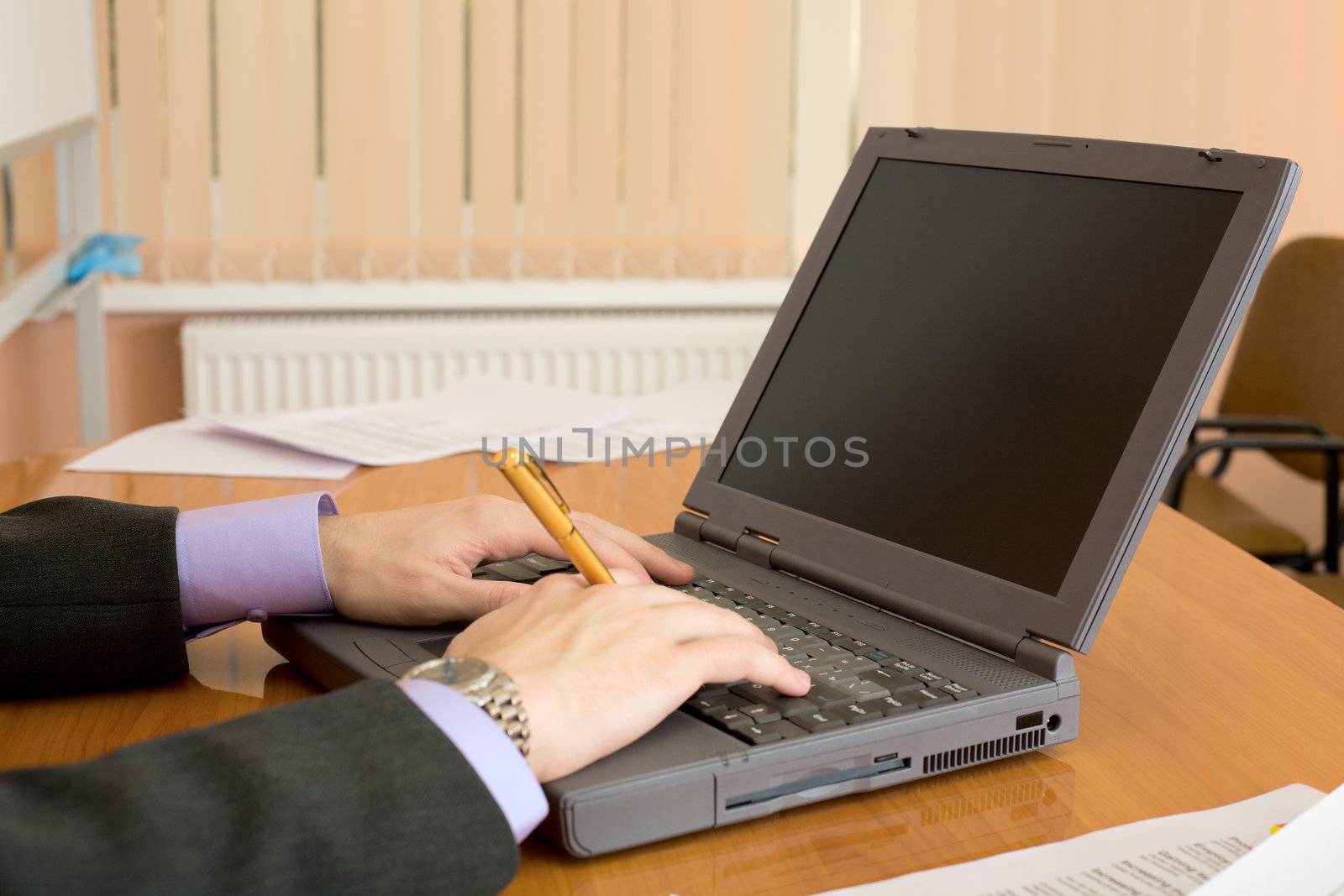 The laptop and man's hands with a pen