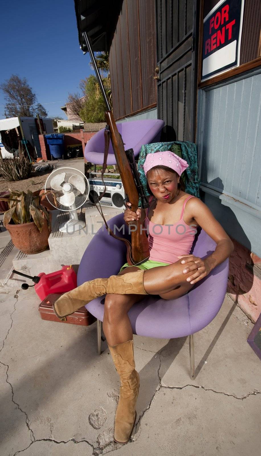 Black woman with rifle in front of house with messy yard