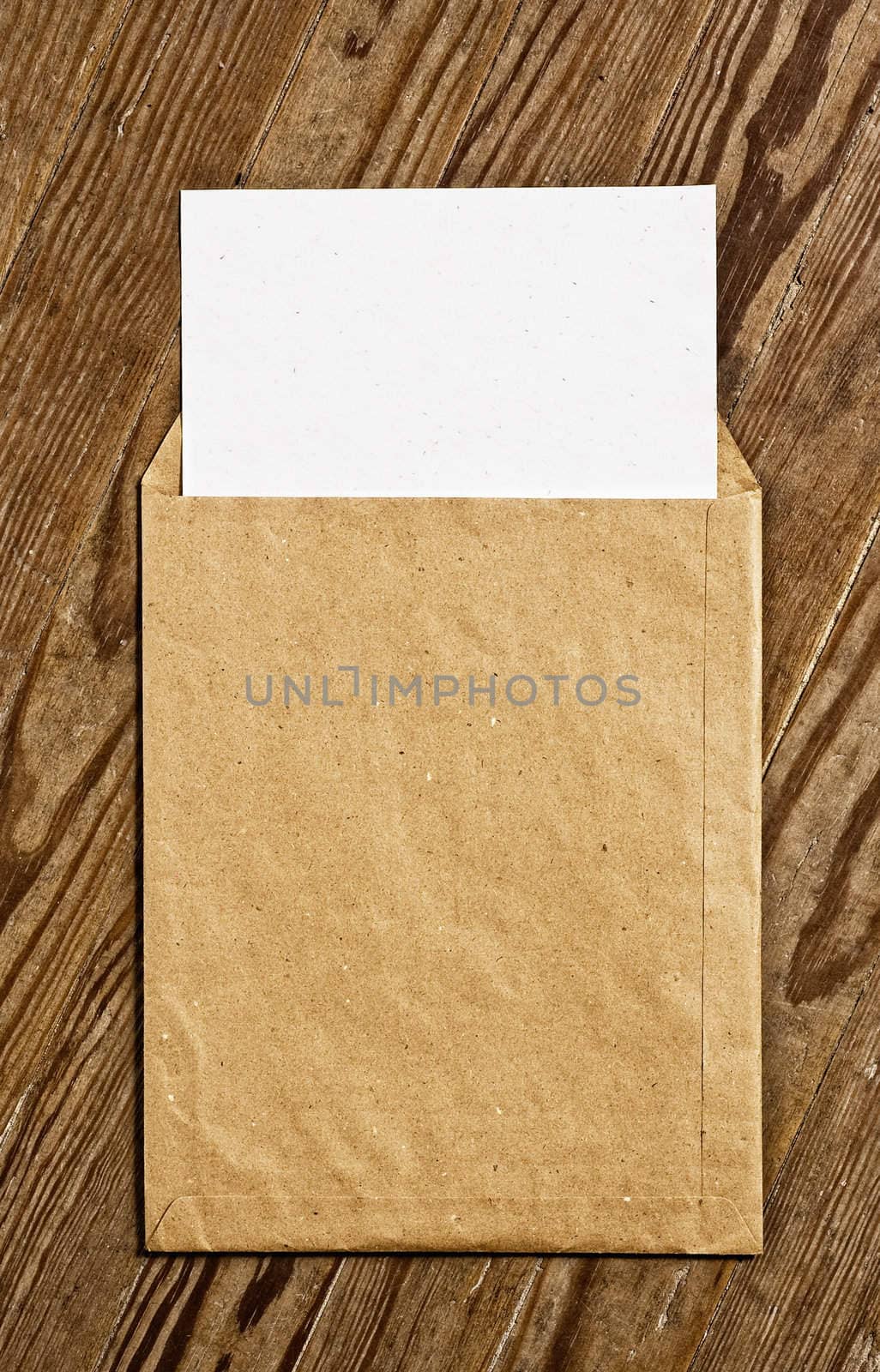 Open Brown Vintage Envelope, with white paper, over wooden surface.