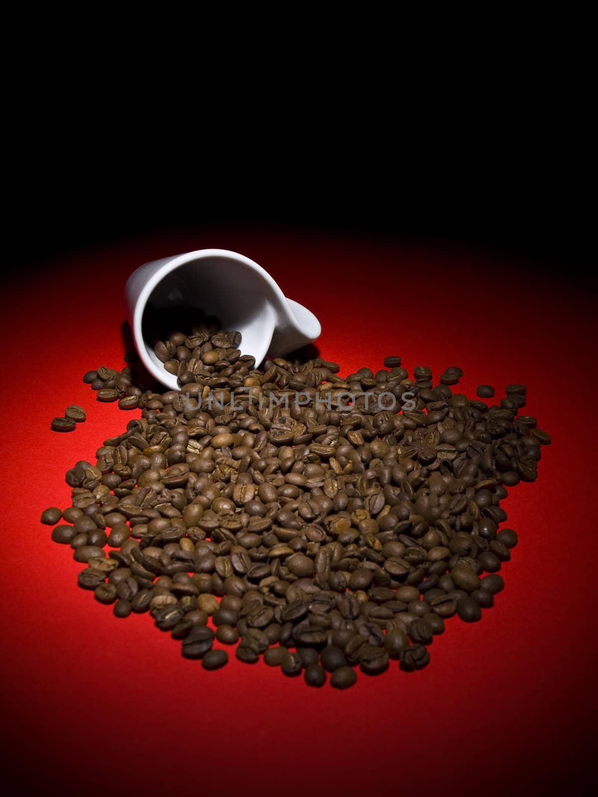 A fallen cup with coffee beans spread out.