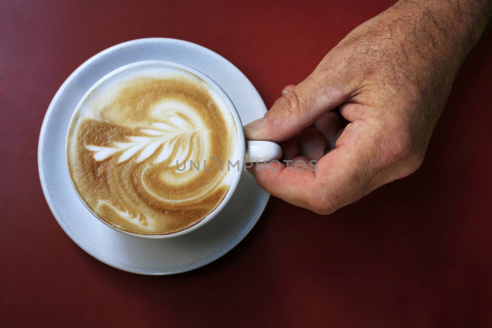 Coffee Latte in a white cup and a man's hand