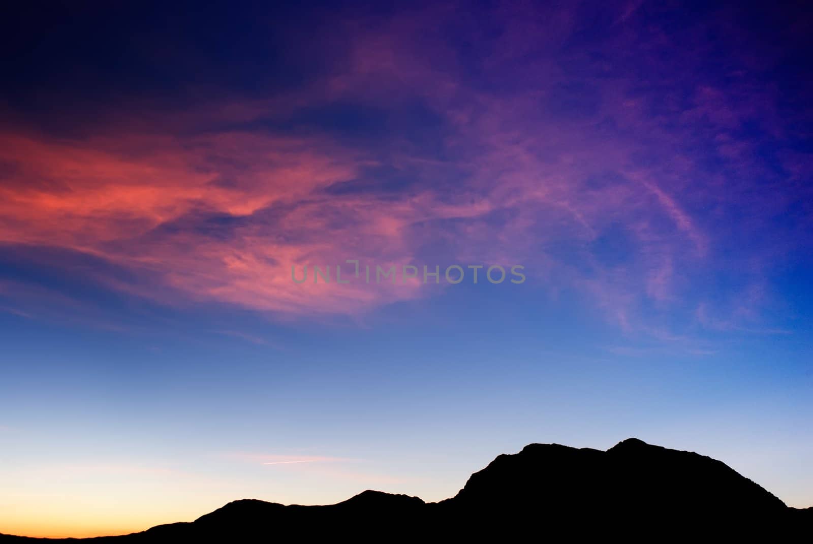 high mountain silhouette with beautiful colorful clouds. by elwynn