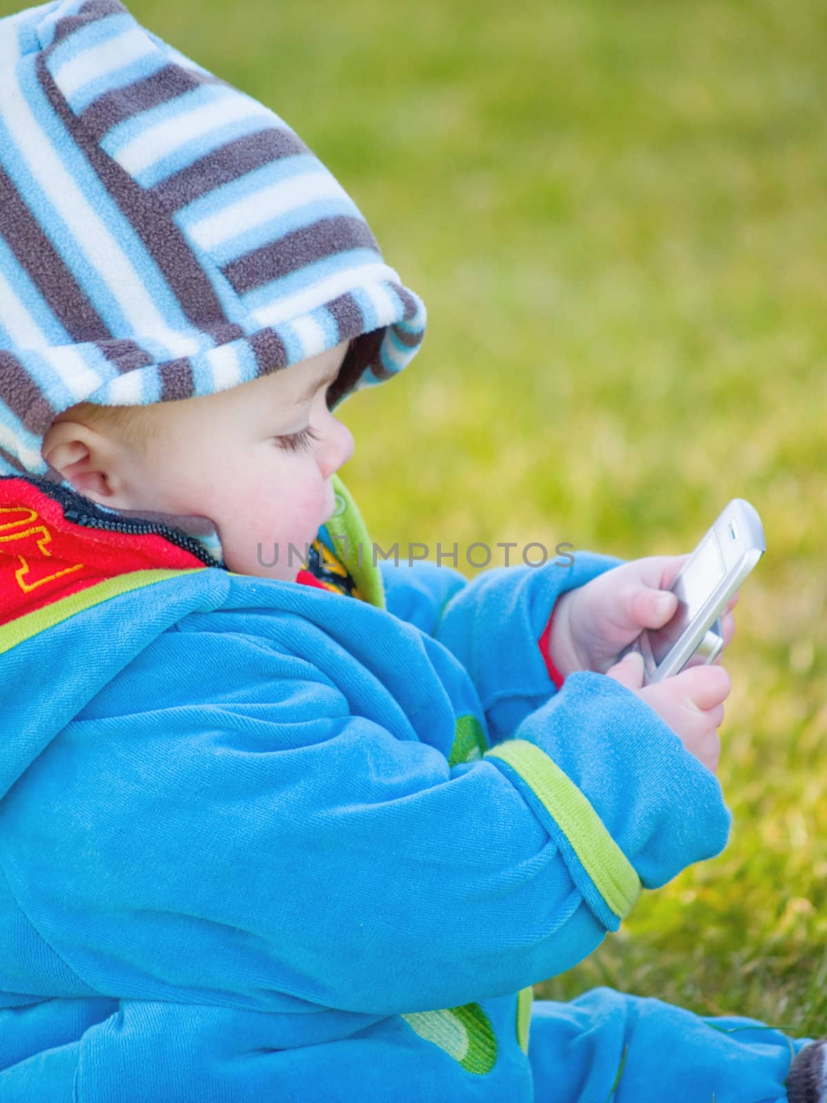 Colourful baby boy playing with cell  phone