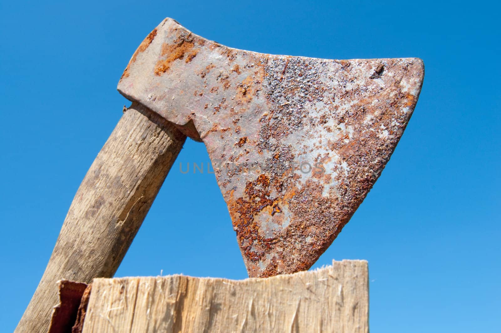 Photo of a rusty ax against the blue sky.