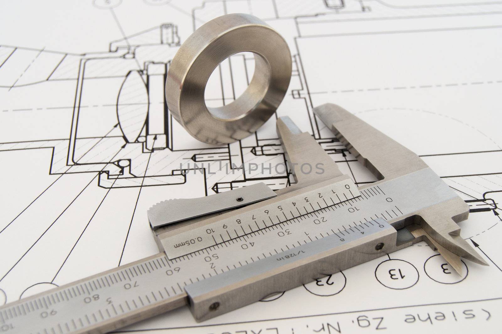 Caliper on technical drawing with work piece.