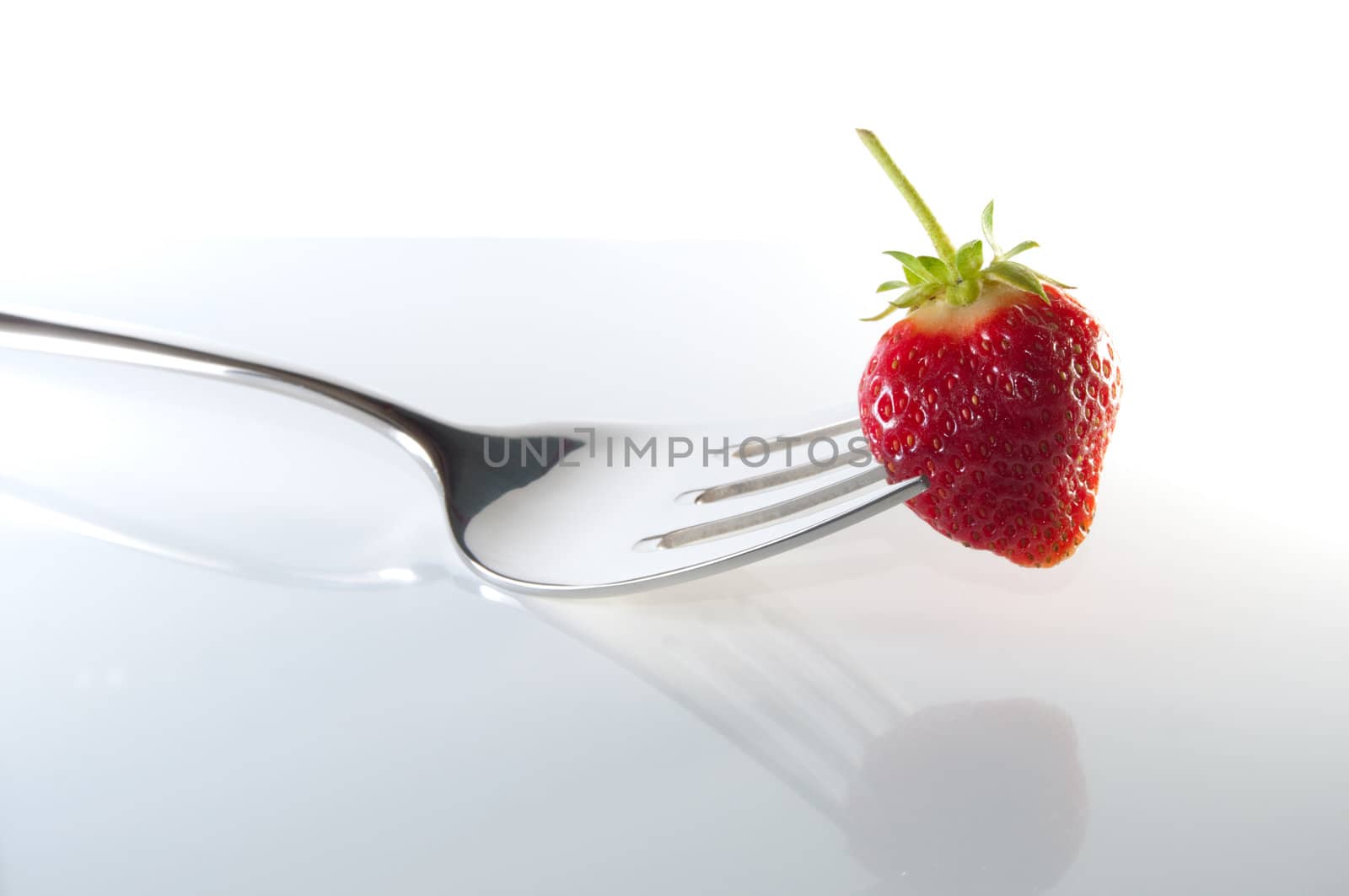 Strawberry on fork impaled.