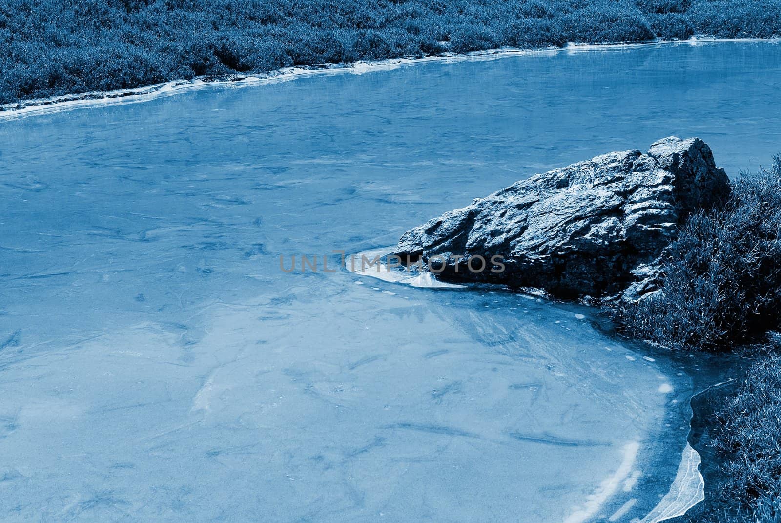 Beautiful strange iced pond surface and rock.