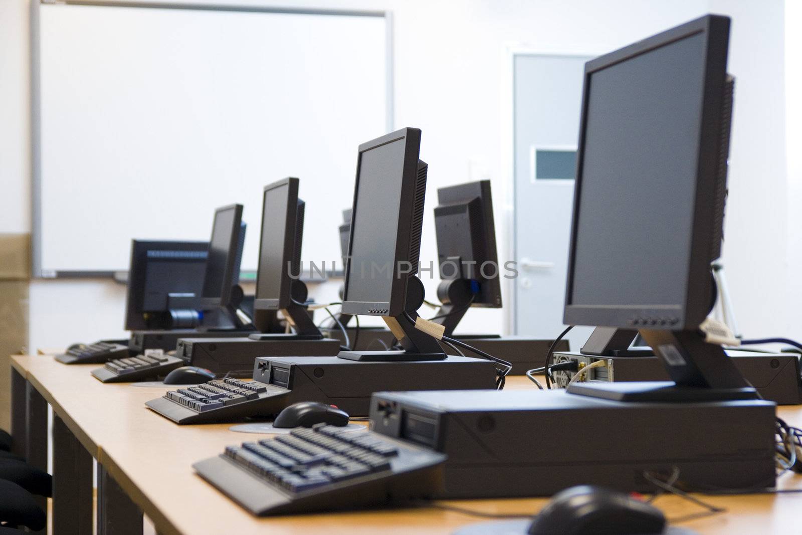 Room equipped with black computers and chairs.