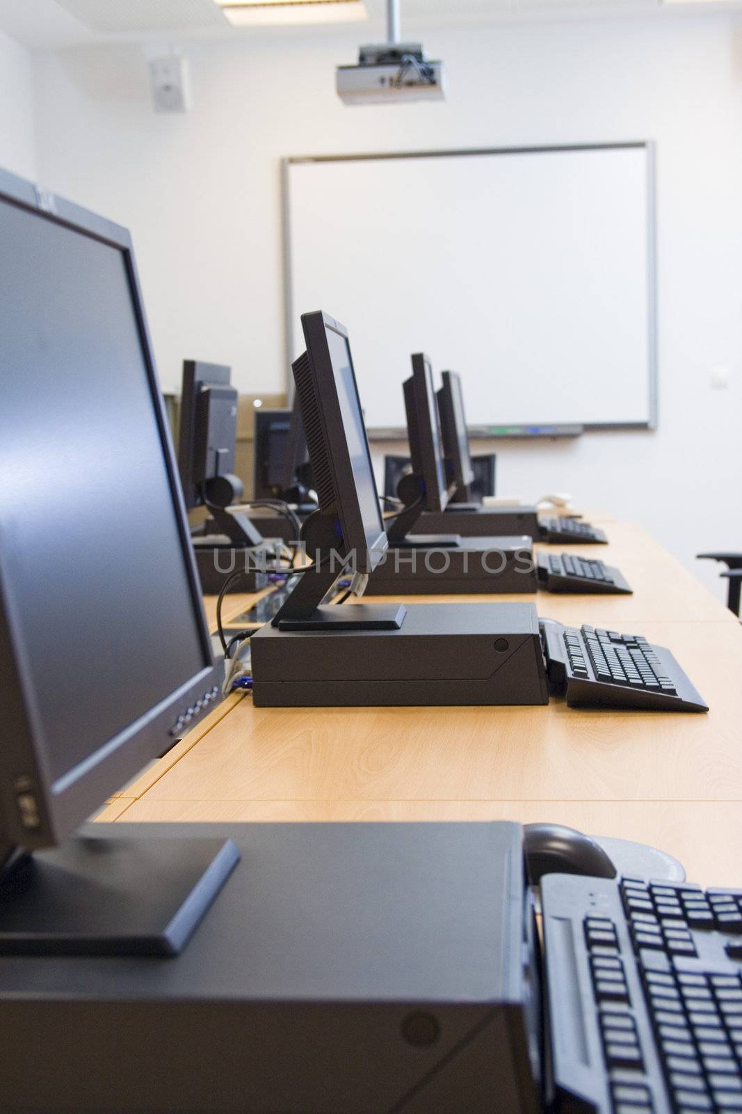 Room equipped with black computers and chairs.