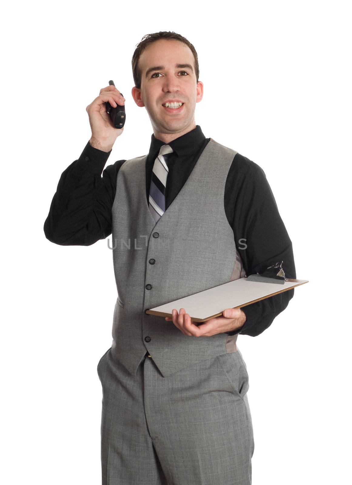 A young man wearing a suit and communicating on a walkie-talkie and holding a clipboard, isolated against a white background