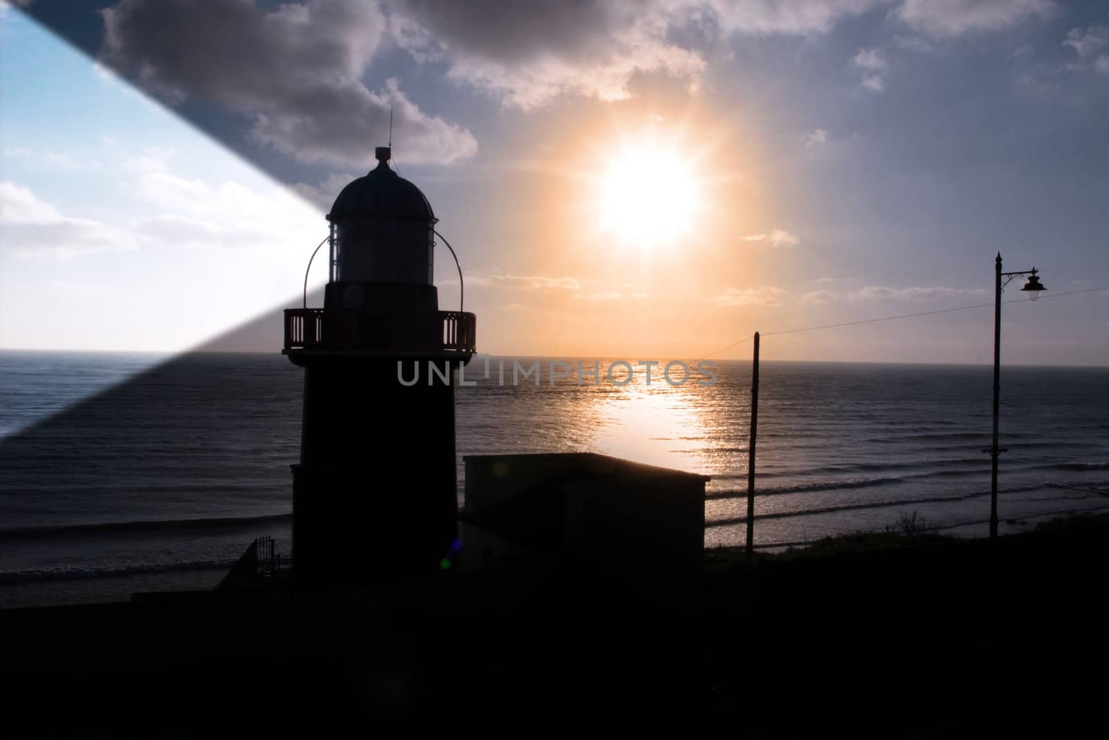 lighthouse captured with the sun behind it and beams on
