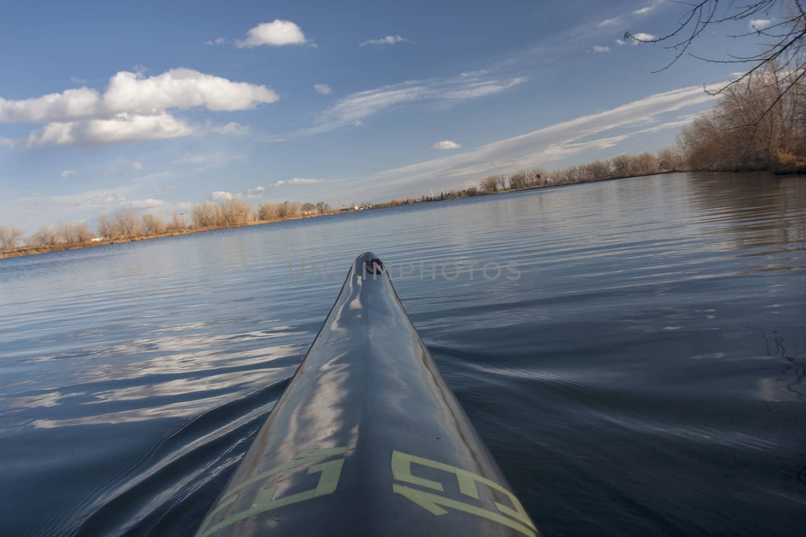 bow of narrow racing kayak turning on calm lake (leaned horizon), early spring in Colorado, thirteen - temporary race number placed on deck by myself