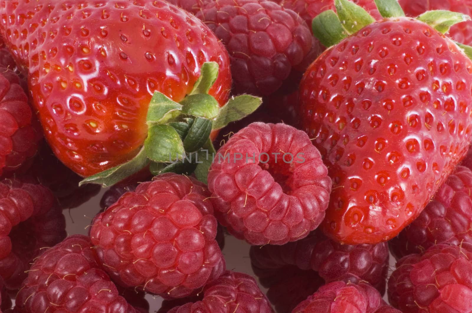 Close up of a bunch of raspberries and strawberries.