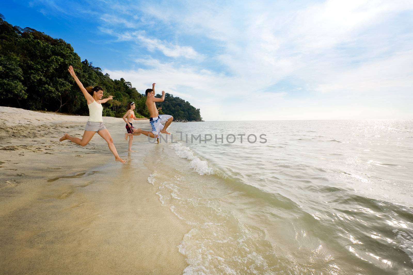 happy friends having fun by the beach jumping into the sea