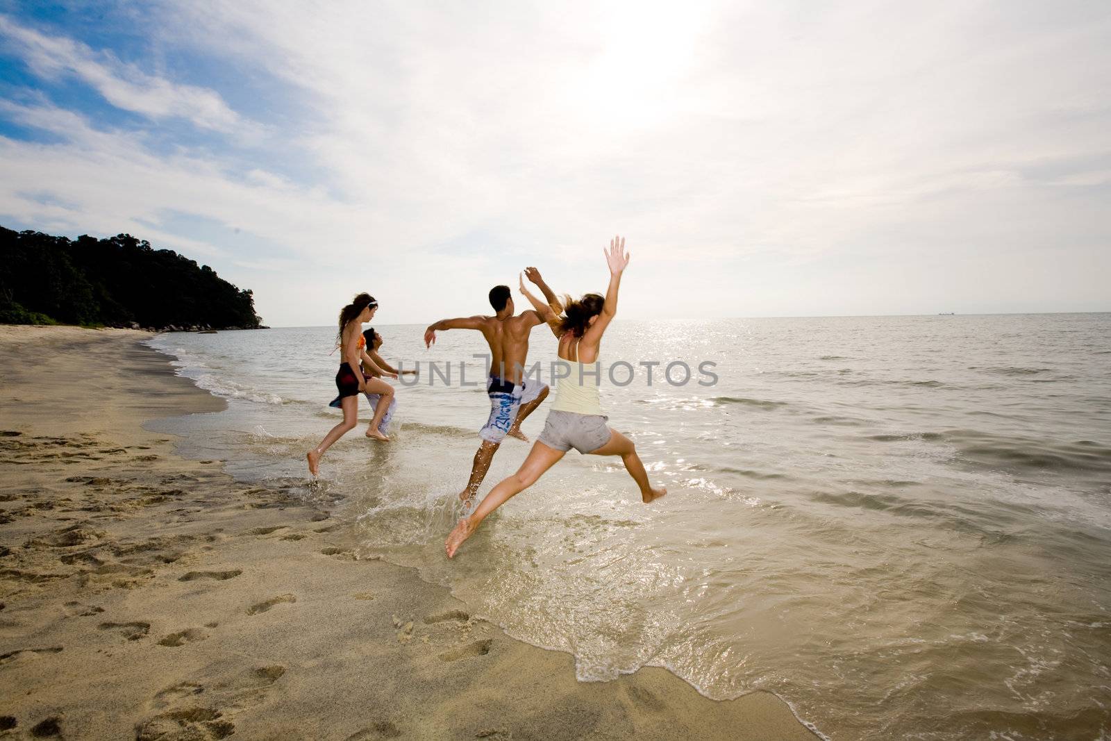 sunset beach with a group of friends having fun jumping