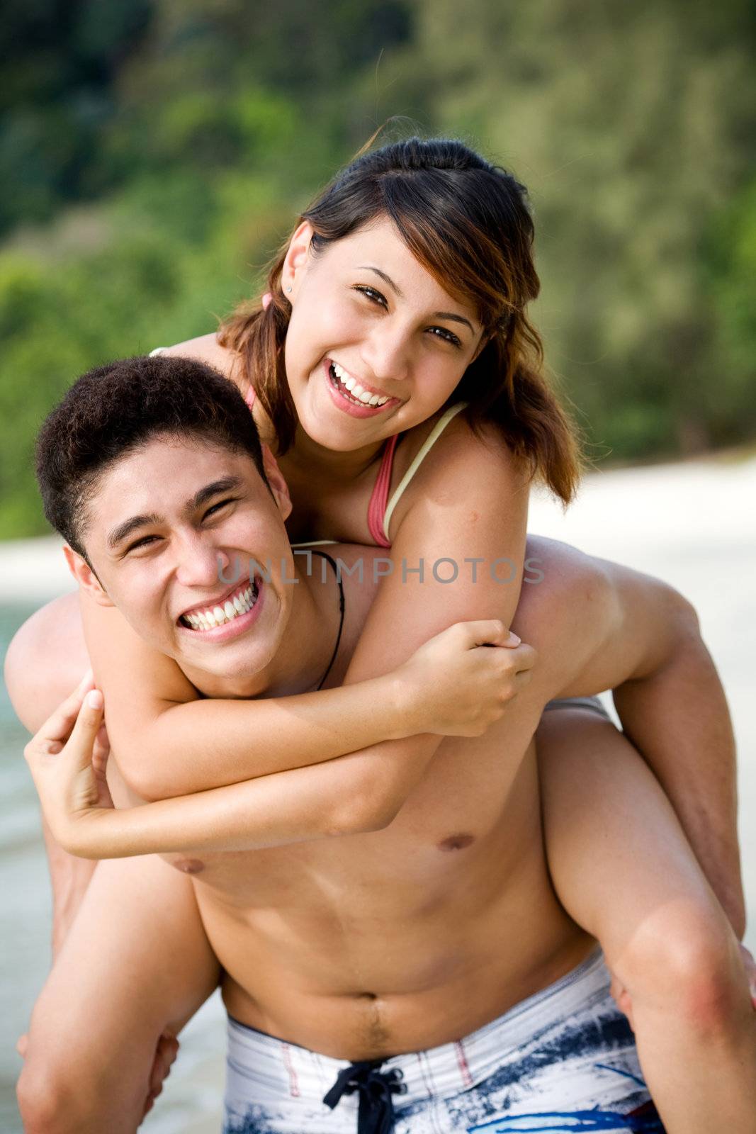 couple having fun at the beach by piggyback carrying
