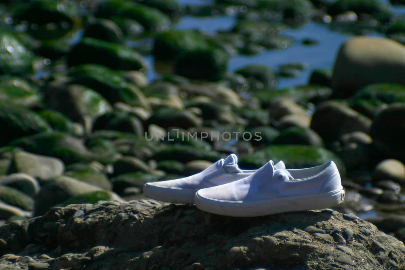A pair of white shoes left alone on the beach