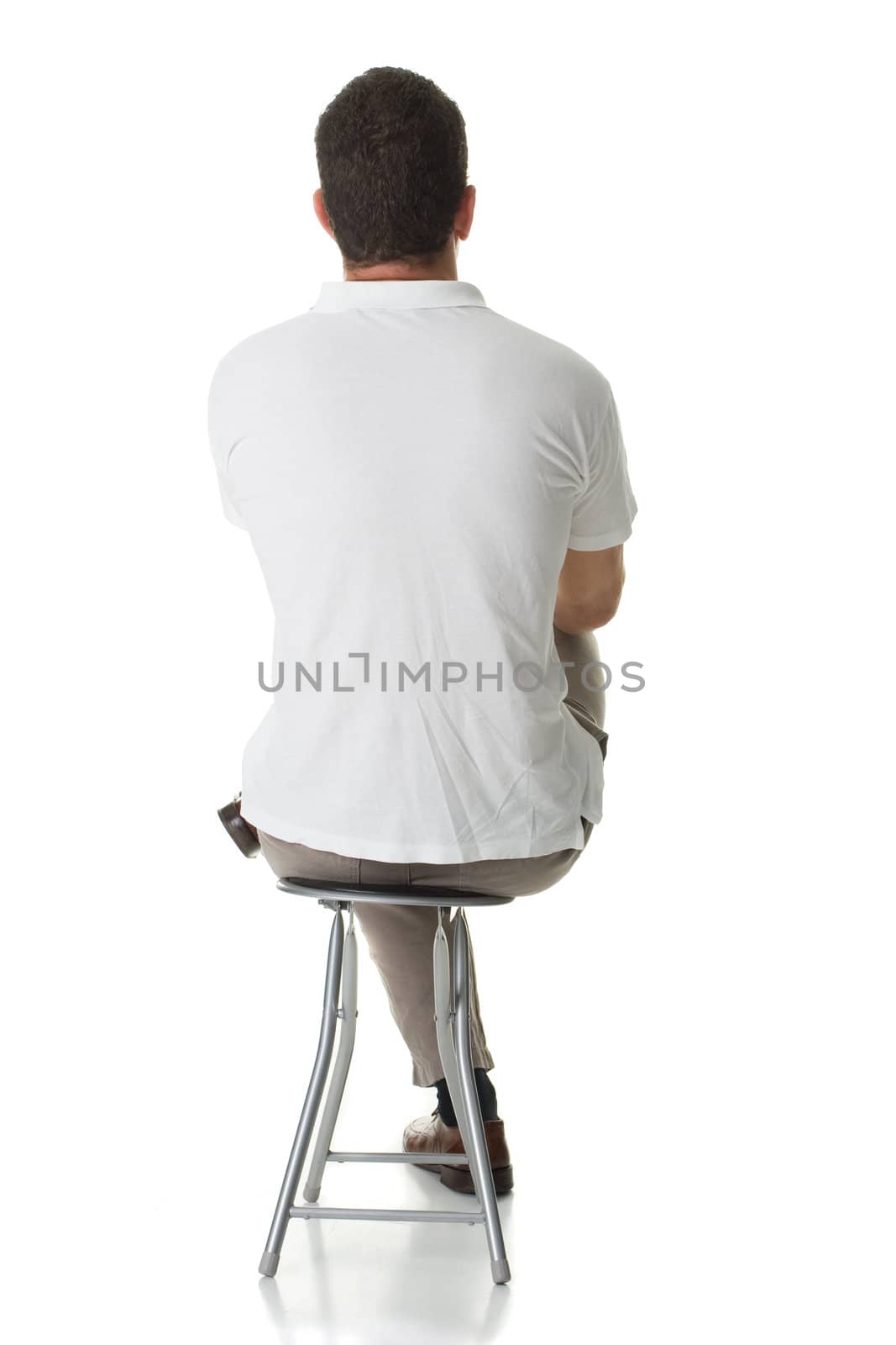 An adult man sitting on a stool, with his back facing the camera.