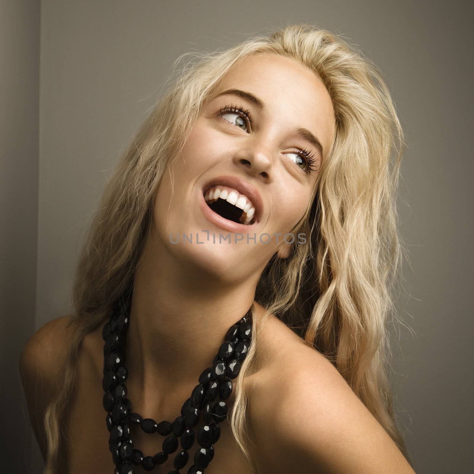 Attractive blonde woman looking to side wearing beaded necklace.