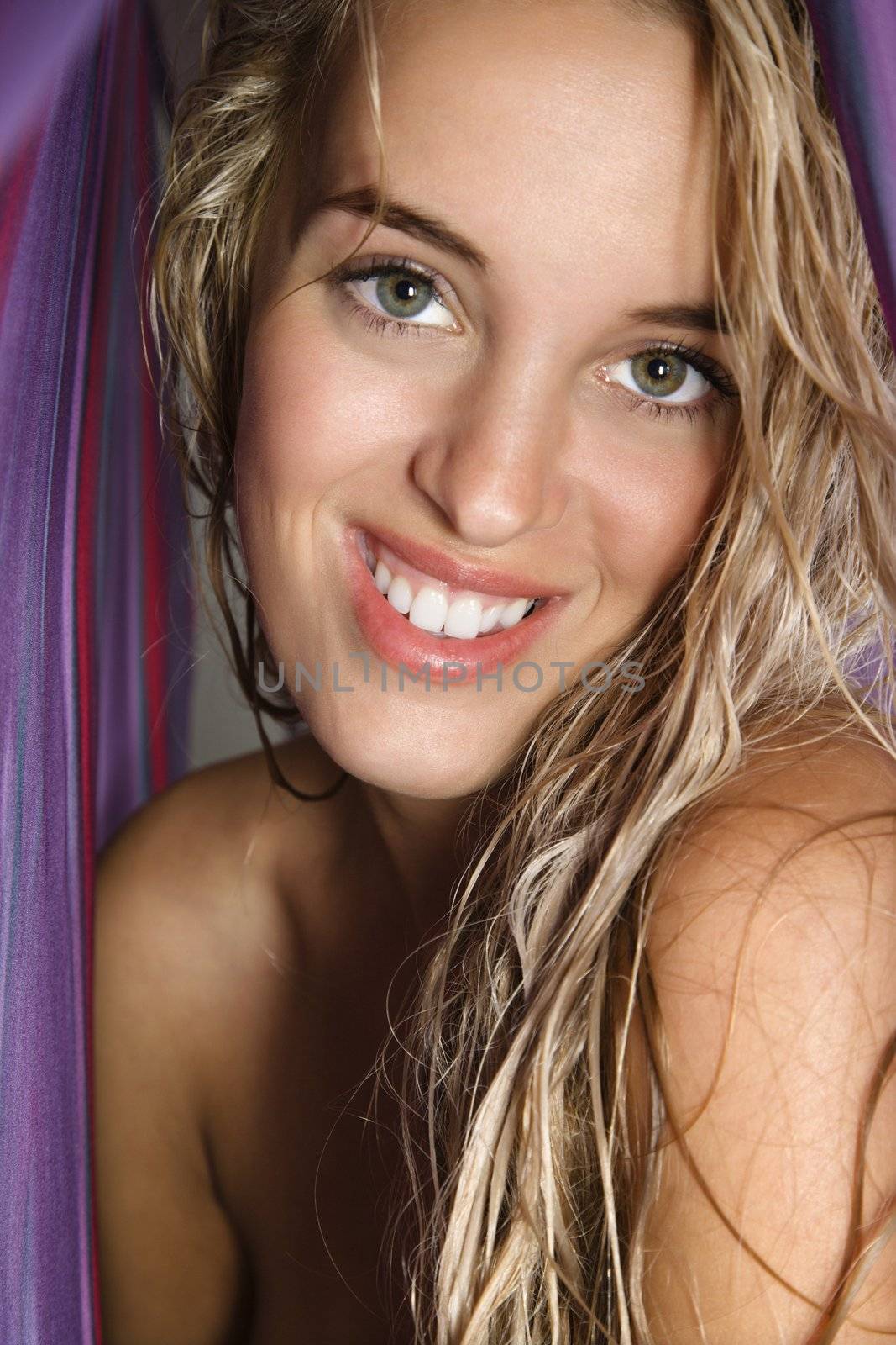Attractive bare Caucasian woman smiling at viewer with long blond hair.