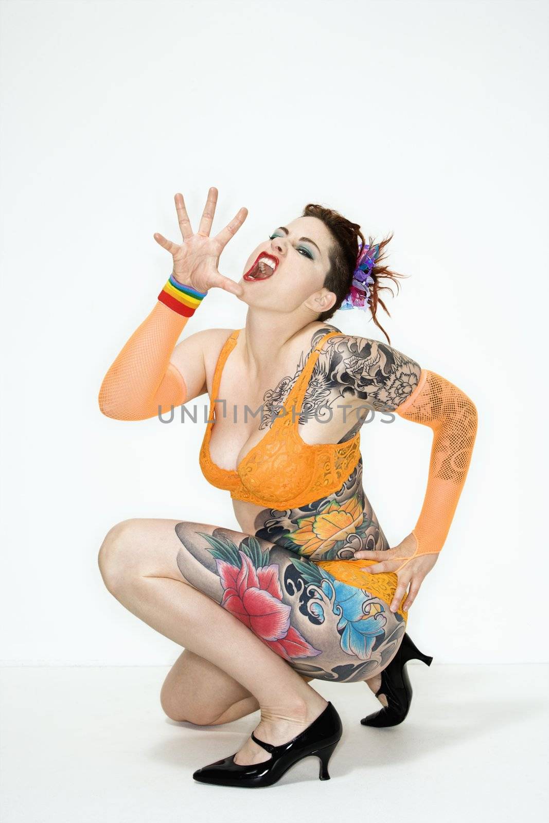 Adult caucasian woman with tattoos squatting on floor with hand out.