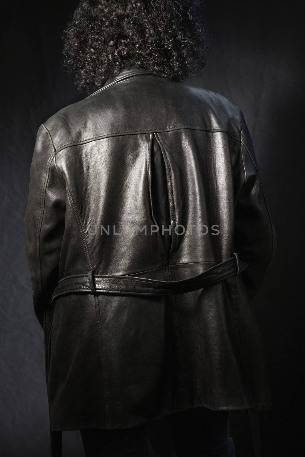 Back view of woman with curly hair wearing black leather jacket.
