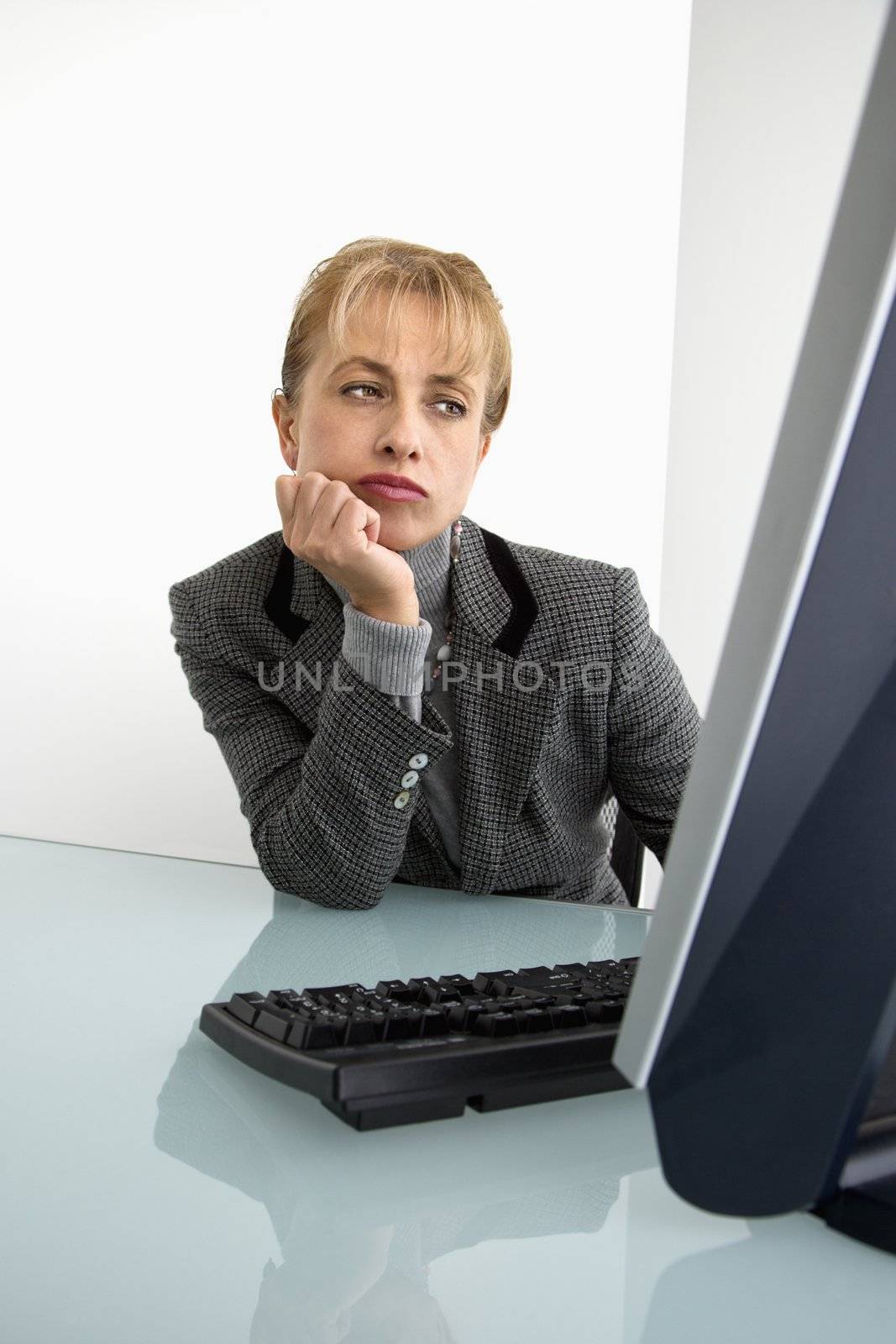 Caucasian woman looking bored at computer.
