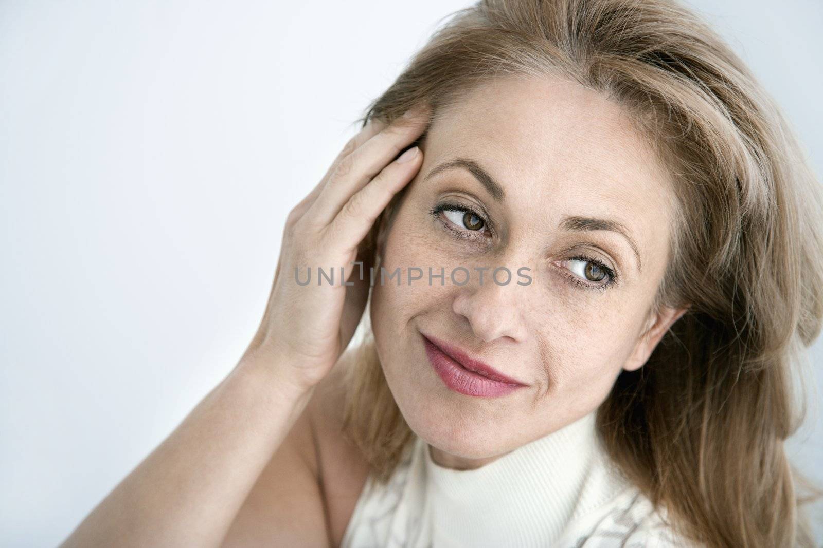 Caucasian woman with hand to head looking away.