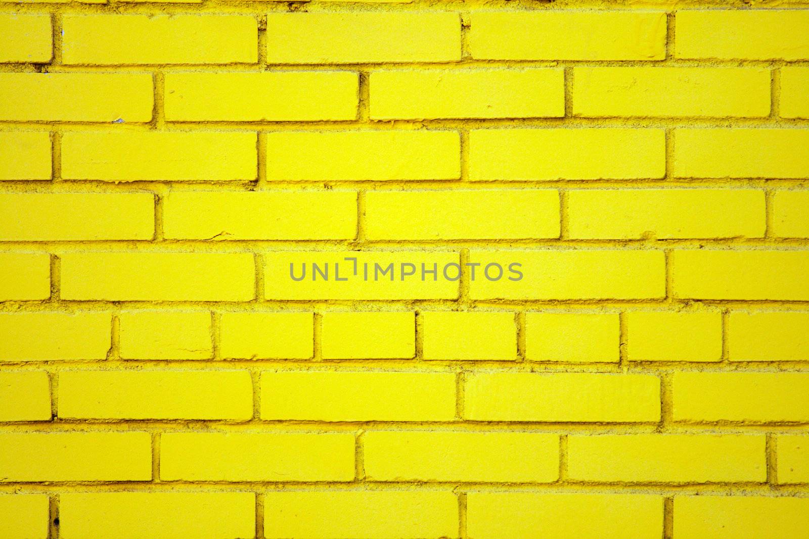 Slightly dusty old brick wall coloured yellow with embedded round closed pipe.
