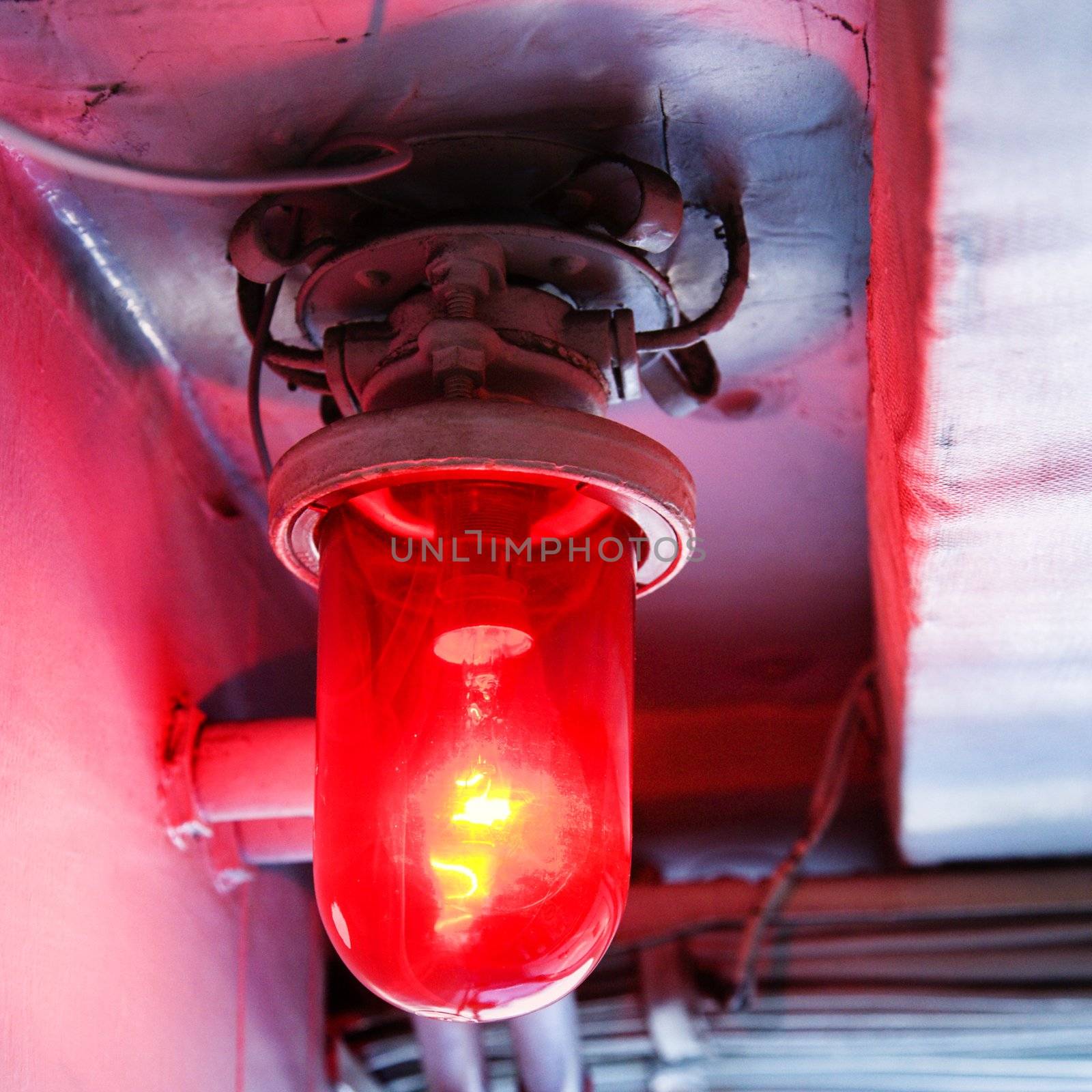Red light bulb glowing from rustic fixture.