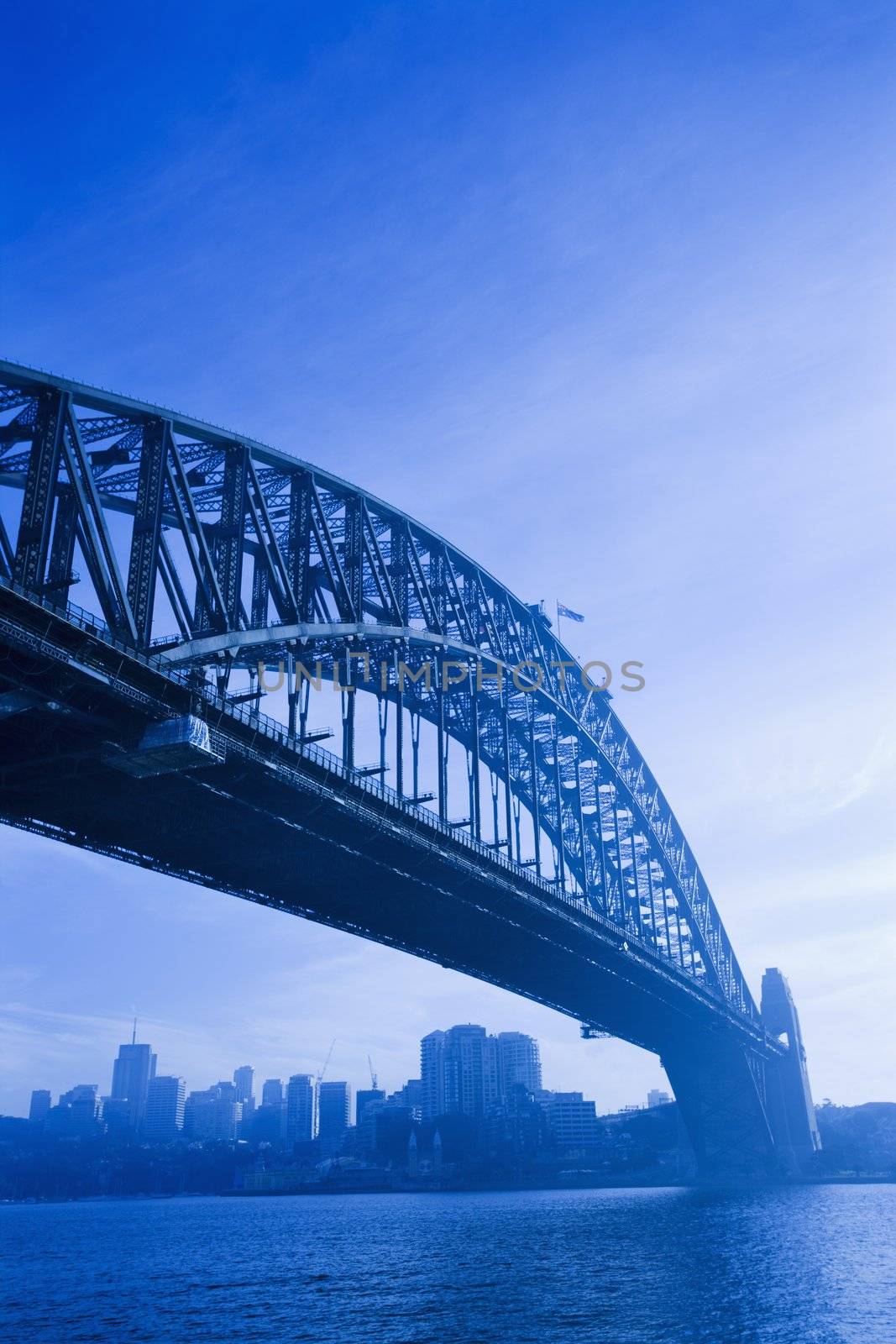 Low angle view of Sydney Harbour Bridge in Australia with view of harbour and downtown skyline.