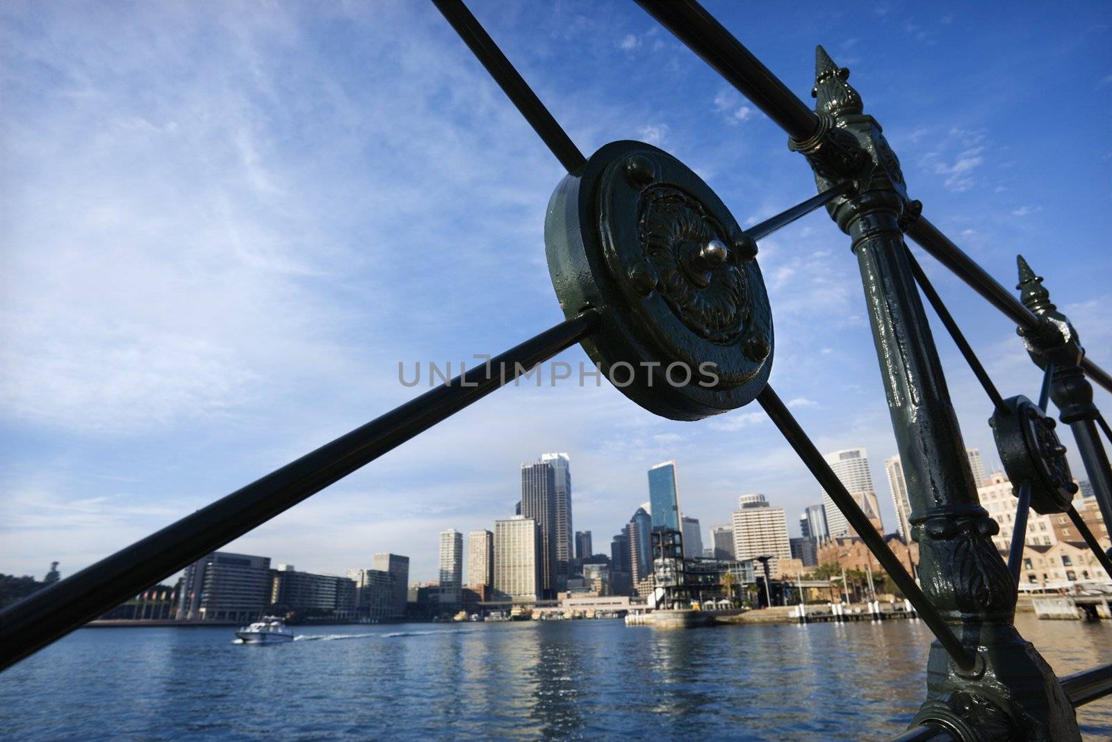 View of Sydney Cove from behind decorative iron railing with city skyline and water in Sydney, Australia.