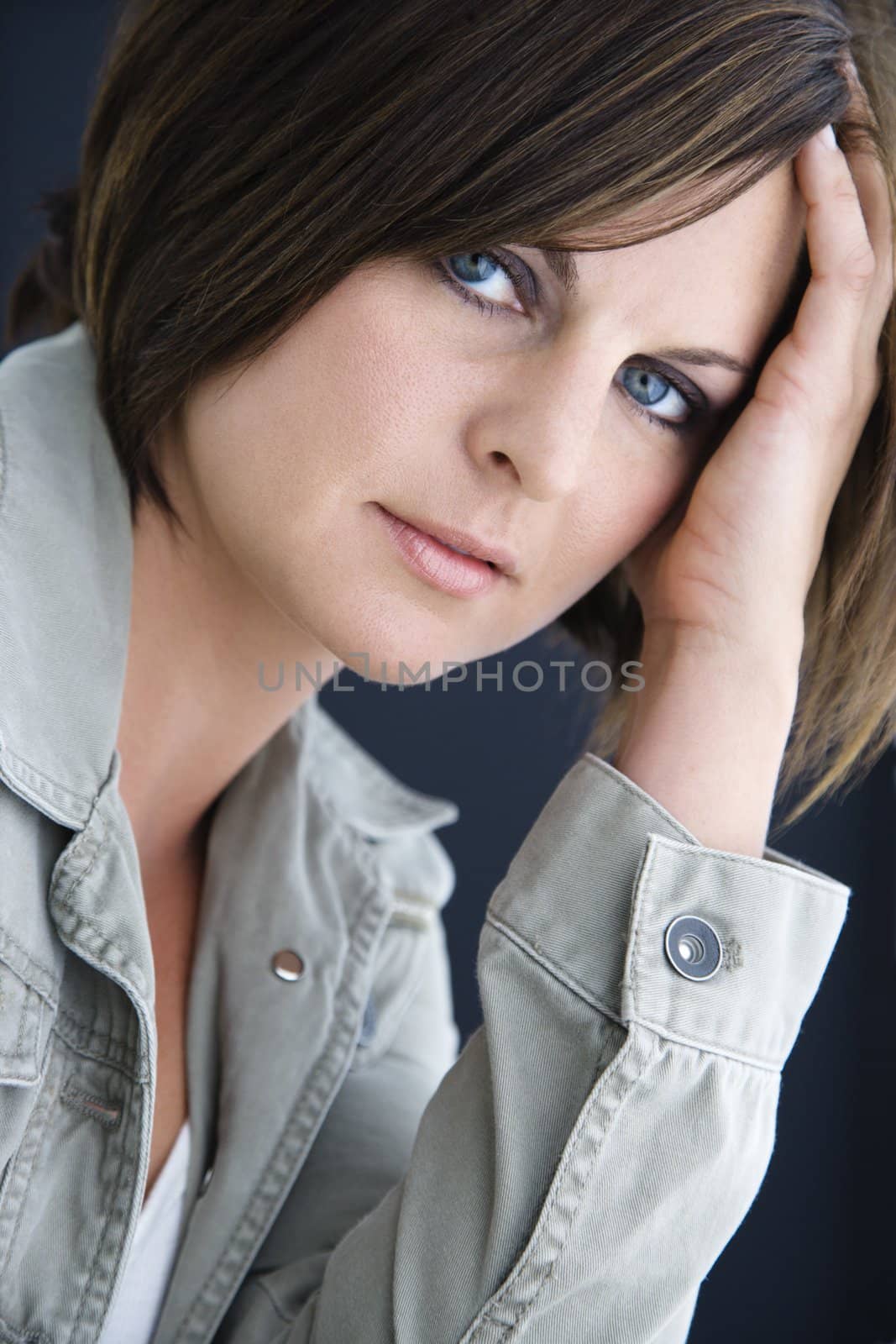 Caucasian mid adult brunette woman looking at viewer resting head on hand.