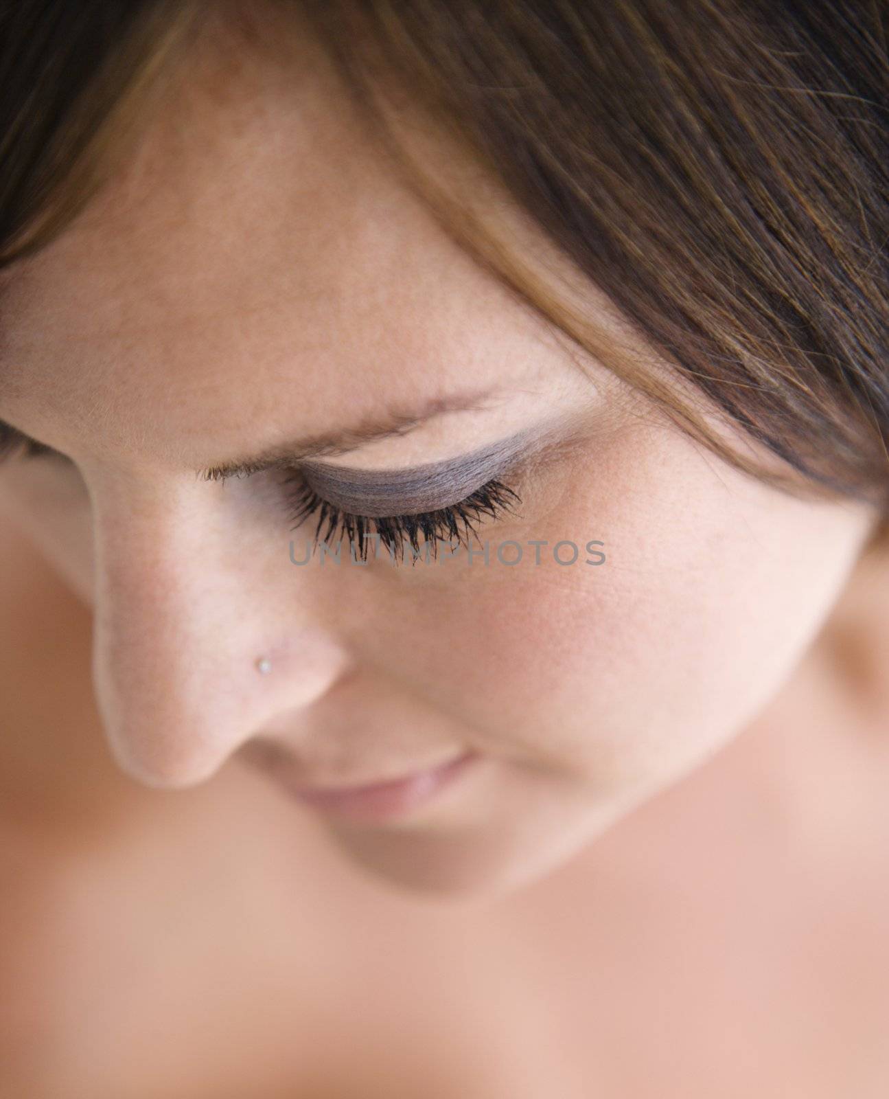 Close up of bare Caucasian mid adult brunette woman with eyes closed.