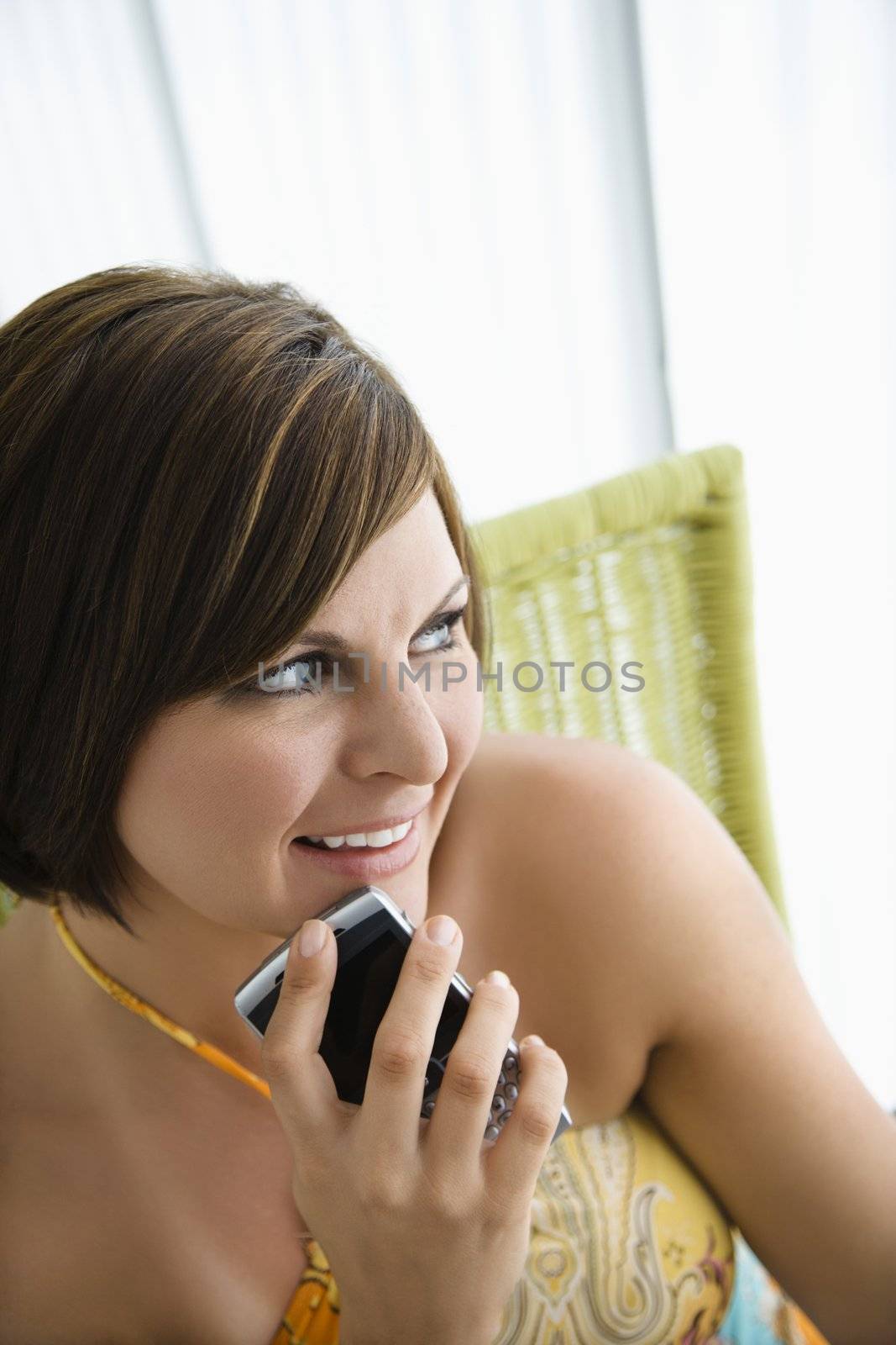 Caucasian mid adult brunette woman holding PDA and smiling.