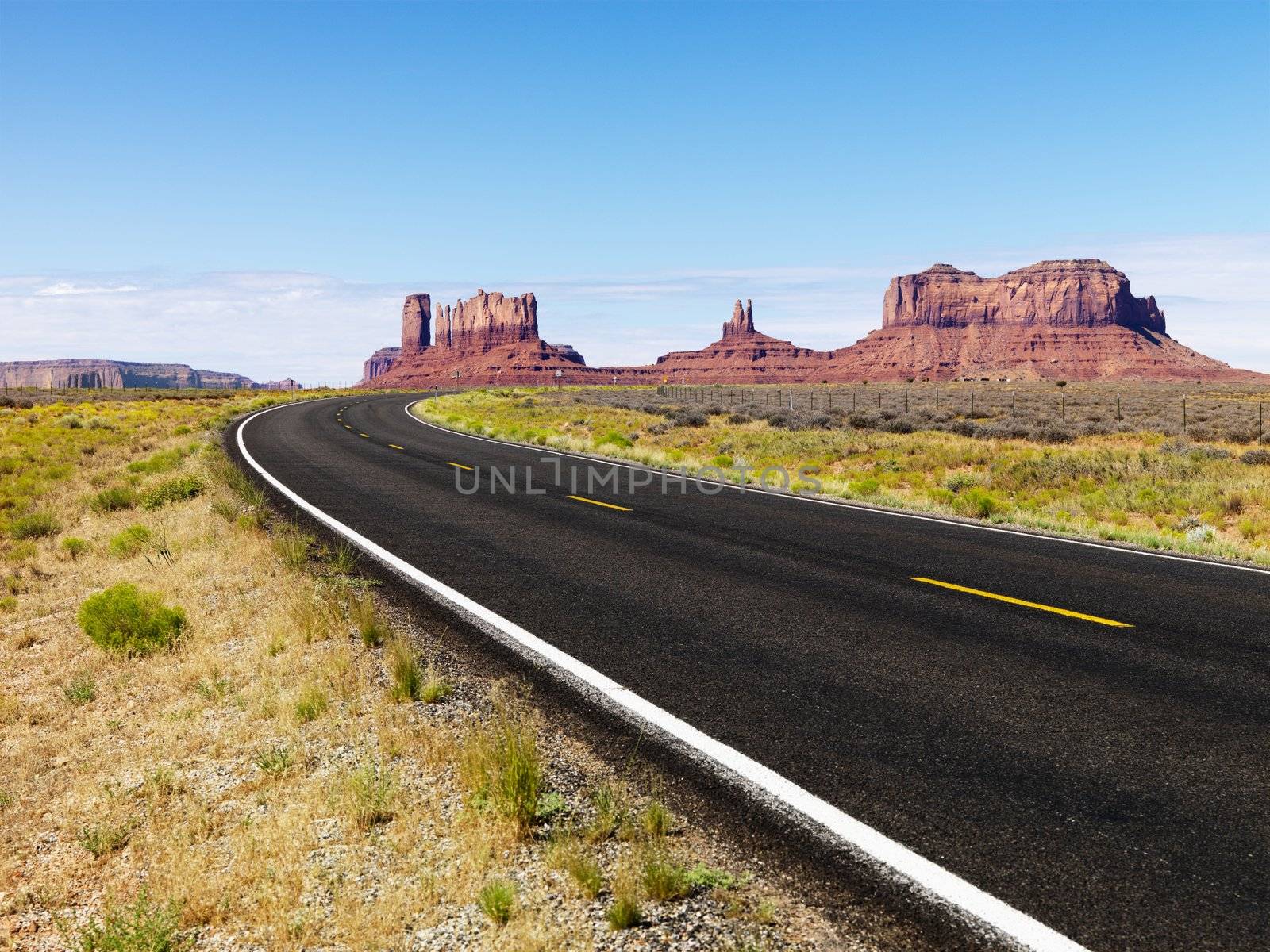 Road in scenic desert landscape with mesa and mountains.