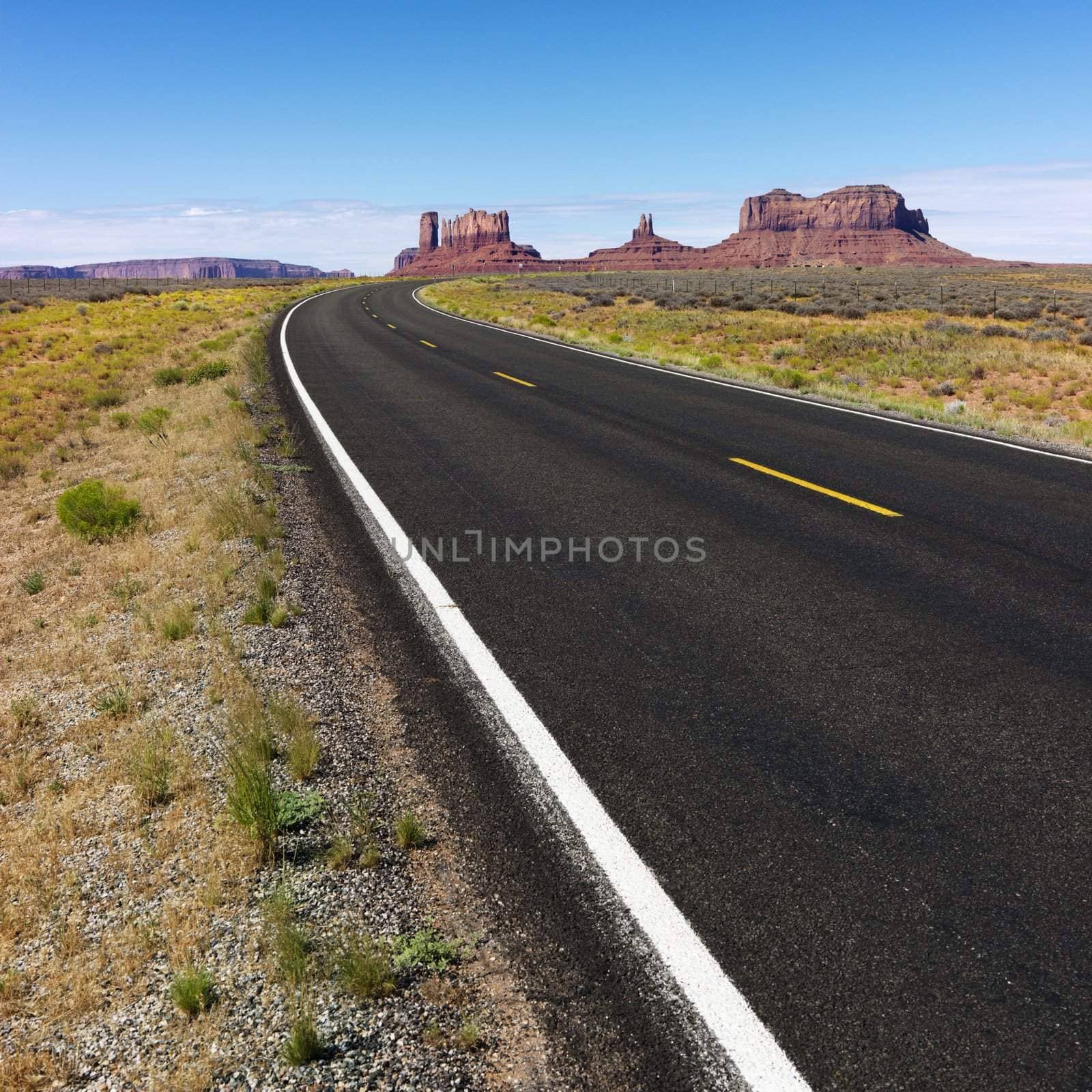 Road in scenic desert landscape with mesa and mountains.