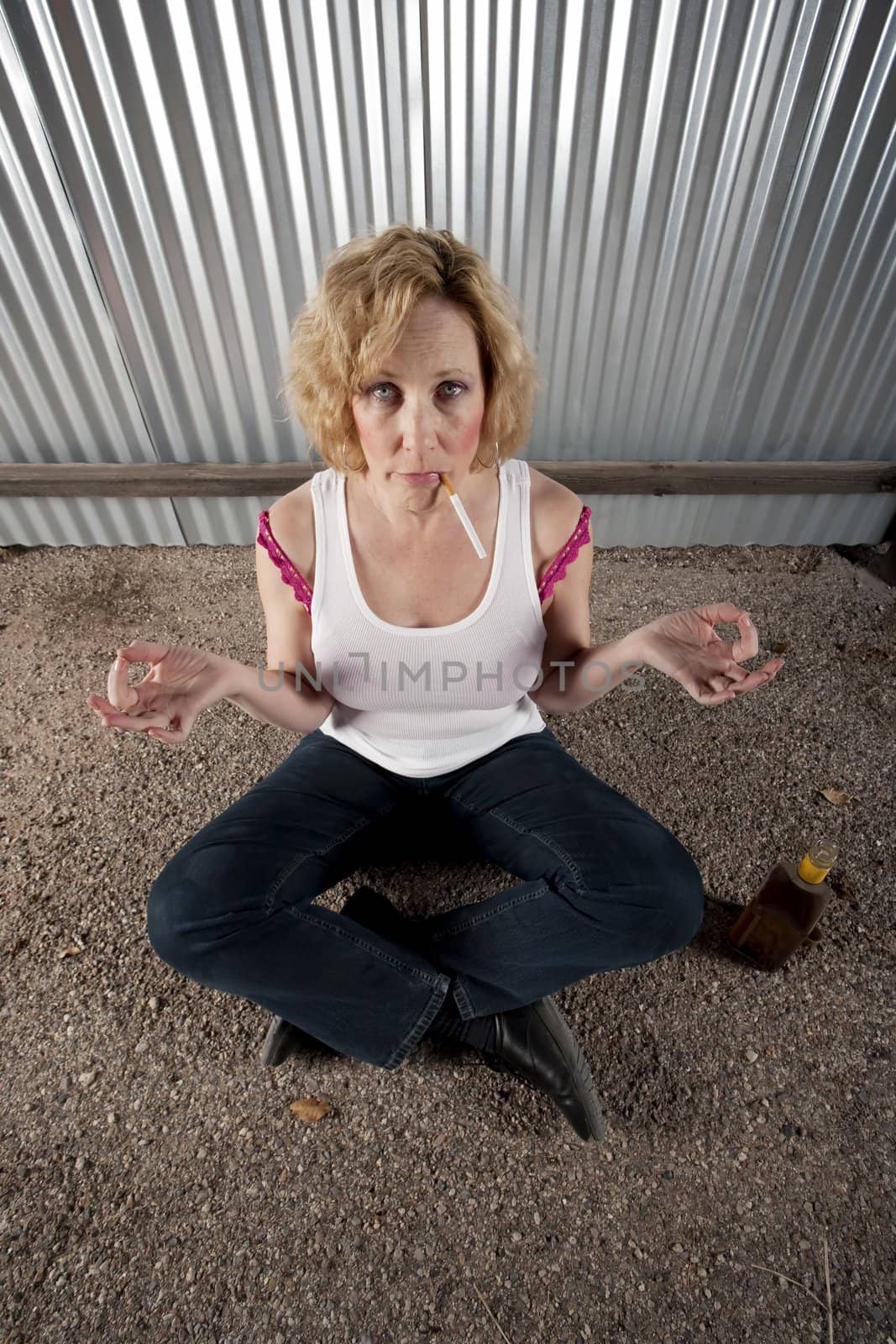 Woman meditating with cigarette and tequila bottle