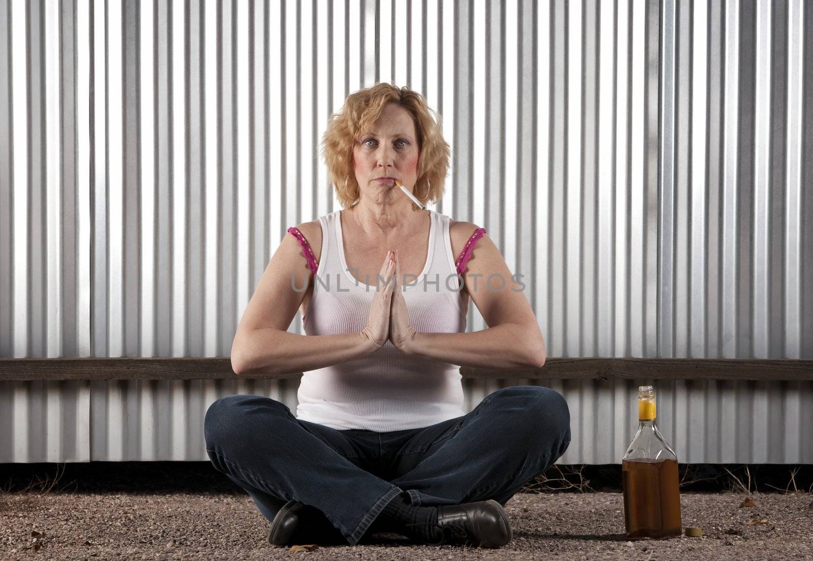 Woman meditating with cigarette and tequila bottle