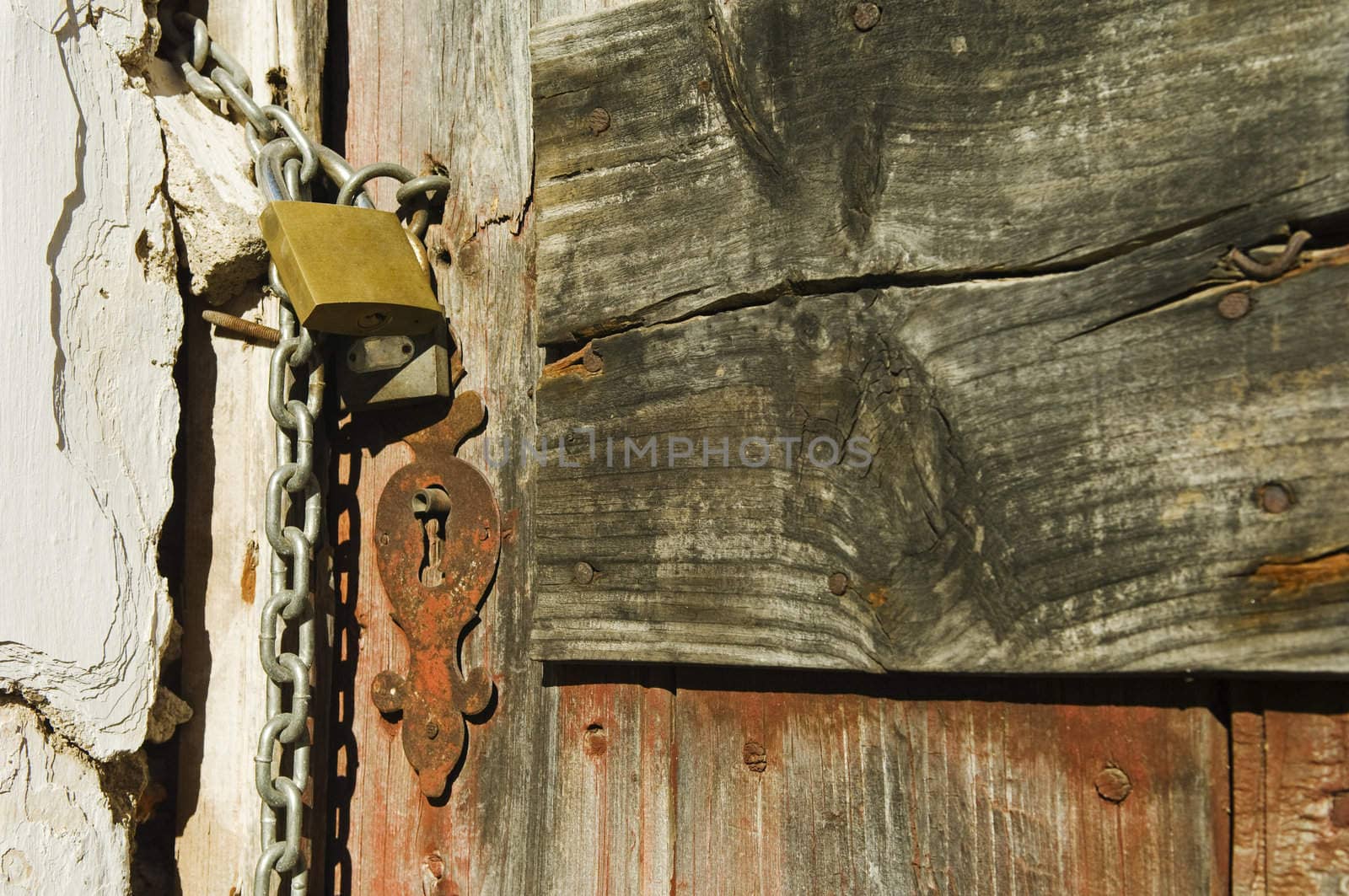 Old drab door secured with a padlock and iron chain.