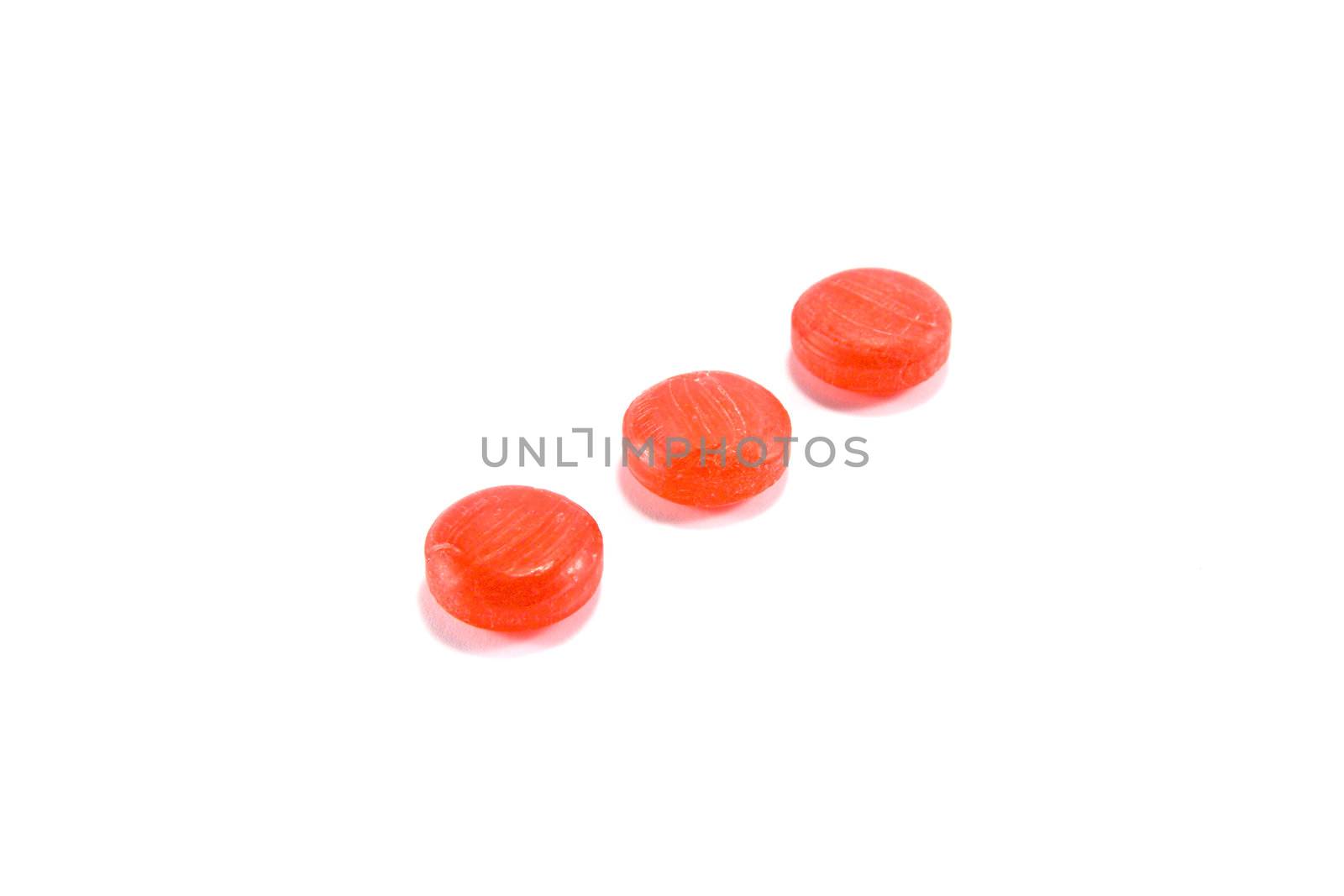 Three red sweets in a line on a white background