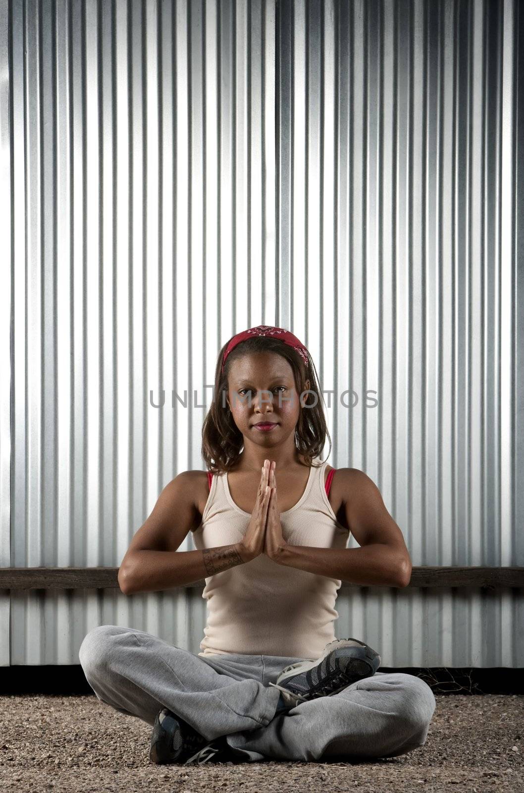 African-American woman meditating in front of corrugated metal